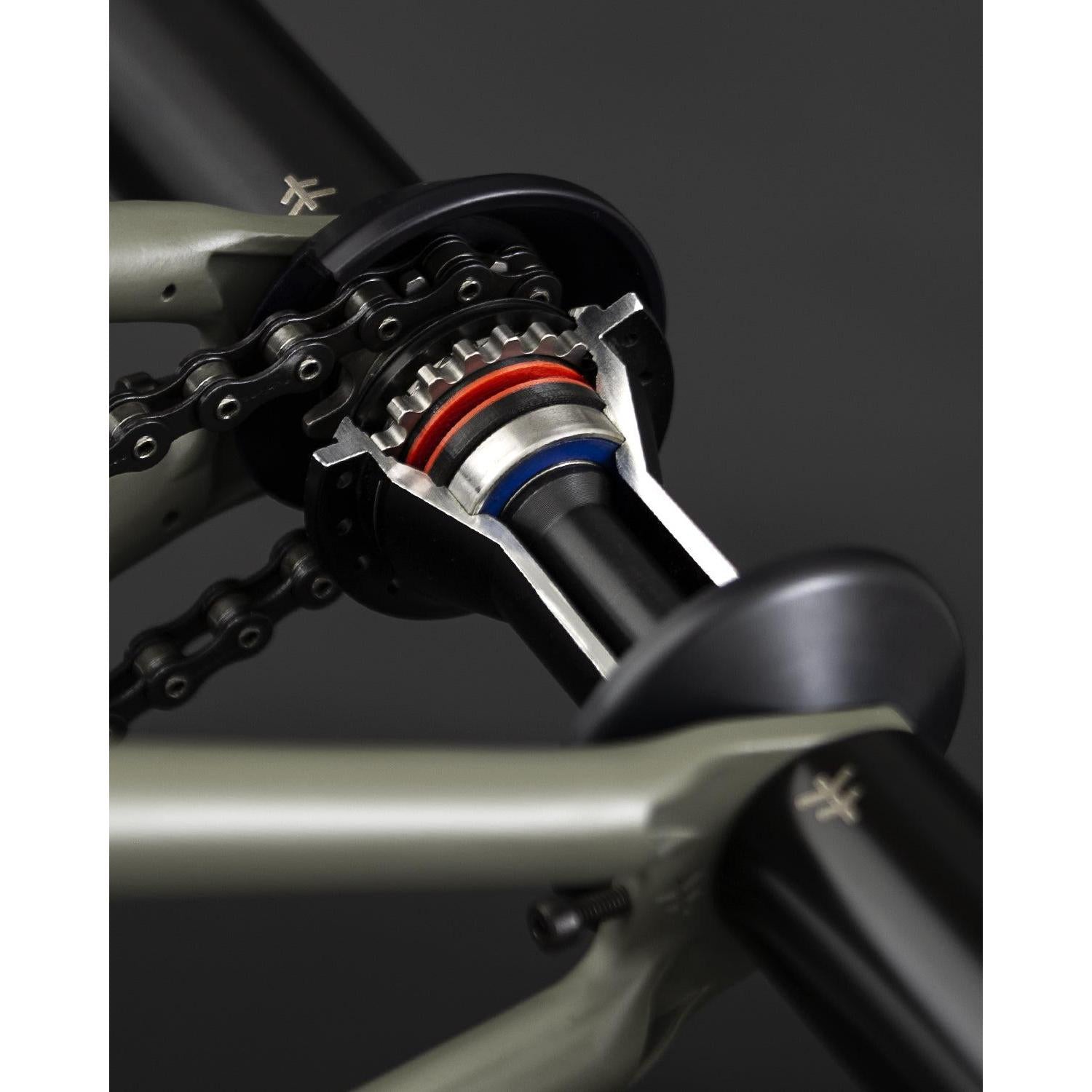 Close-up of the Fly Bikes Magneto Hub Set (Crmo) with oversized bearings, highlighting the chain and gear mechanism against a dark background.