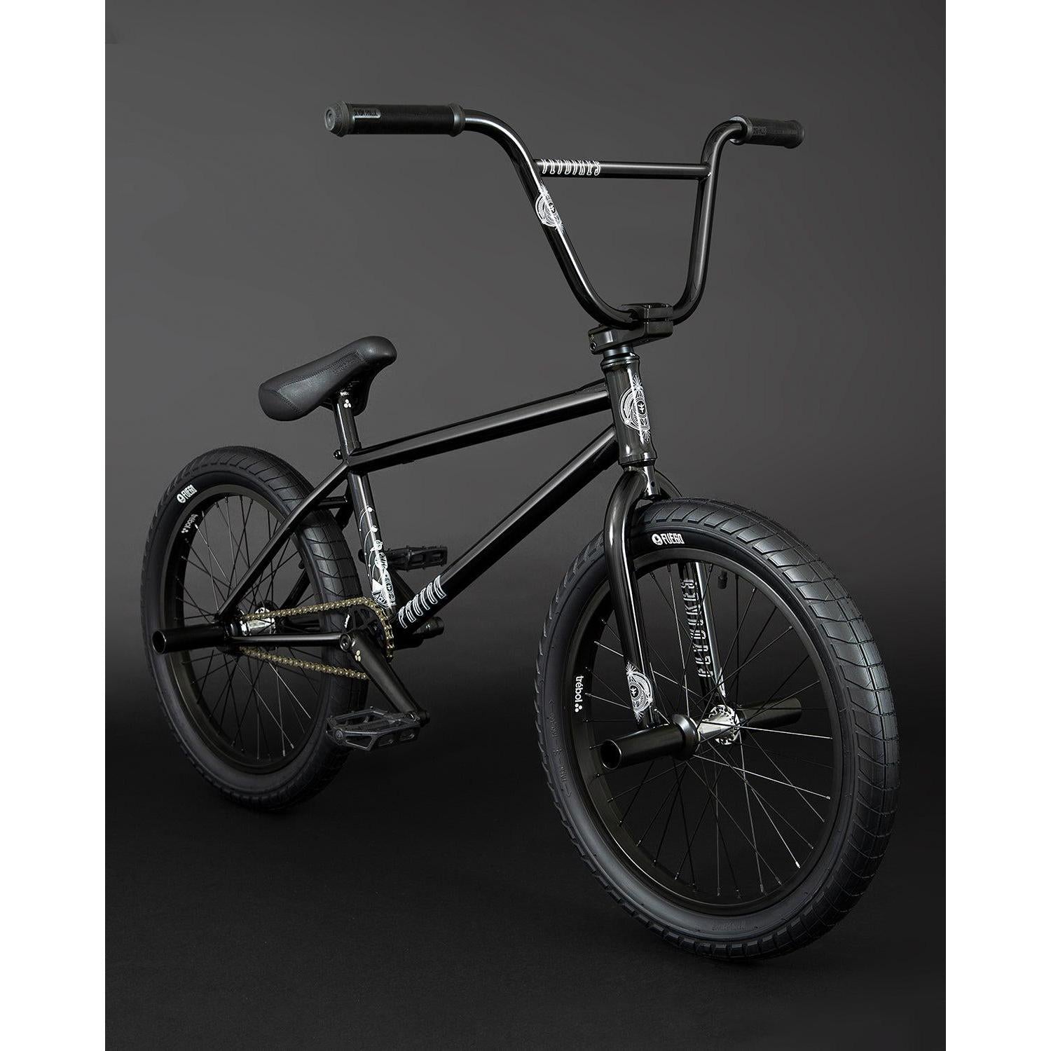 The Fly Bikes Proton FC 20 Inch Bike showcases a CrMo frame with thick tires and straight handlebars, designed for smooth rides with its sealed hubs, all set against a dark background.
