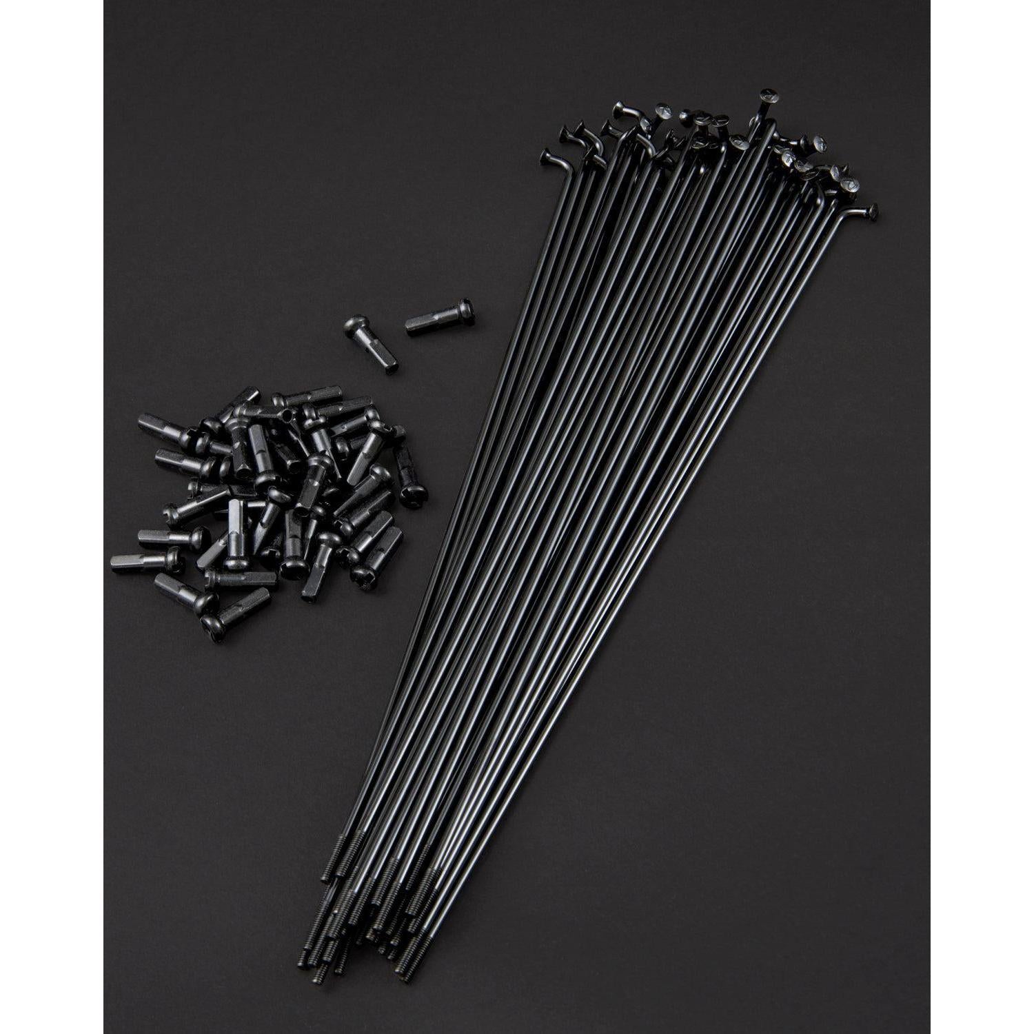 Fly Bikes Spokes (20 Pack) in black and stainless steel nipples are displayed on a dark surface, highlighting the precision of high-tension lacing.