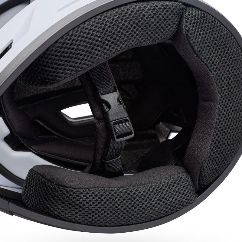 Close-up of the Bell Sanction 2 White helmet interior, highlighting its padded lining, mesh fabric, and adjustable chin strap with a plastic buckle—ideal features for an entry-level or kids' bike helmet.