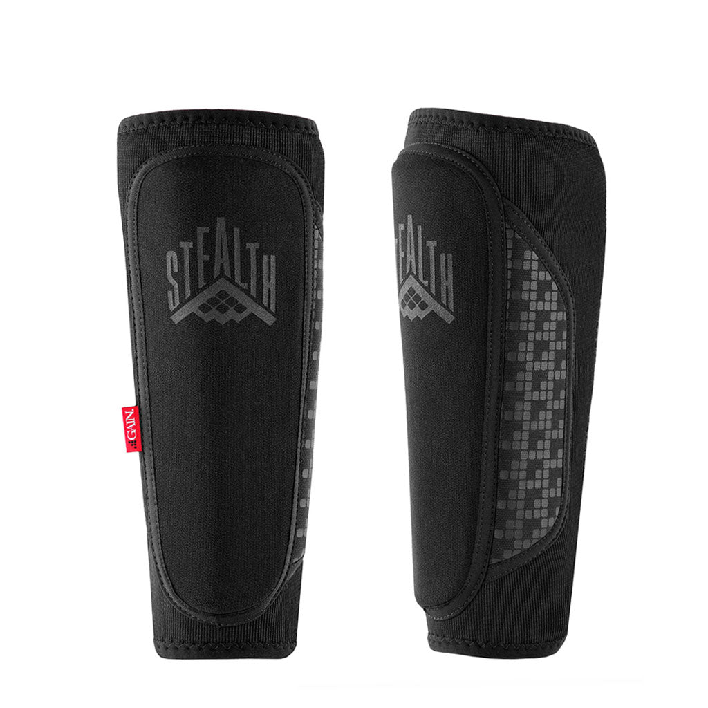The GAIN STEALTH Shin Guards (Pair) are black with "STEALTH" and a graphic on the front, feature a red side tag, and offer enhanced kevlar shin protection for added durability.