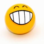 The Grinner Schrader Valve Caps (Pair) are yellow, round, and feature a big smiling face with closed eyes—perfect for adding playful charm to your bike or for unicycle fans seeking a quirky touch.