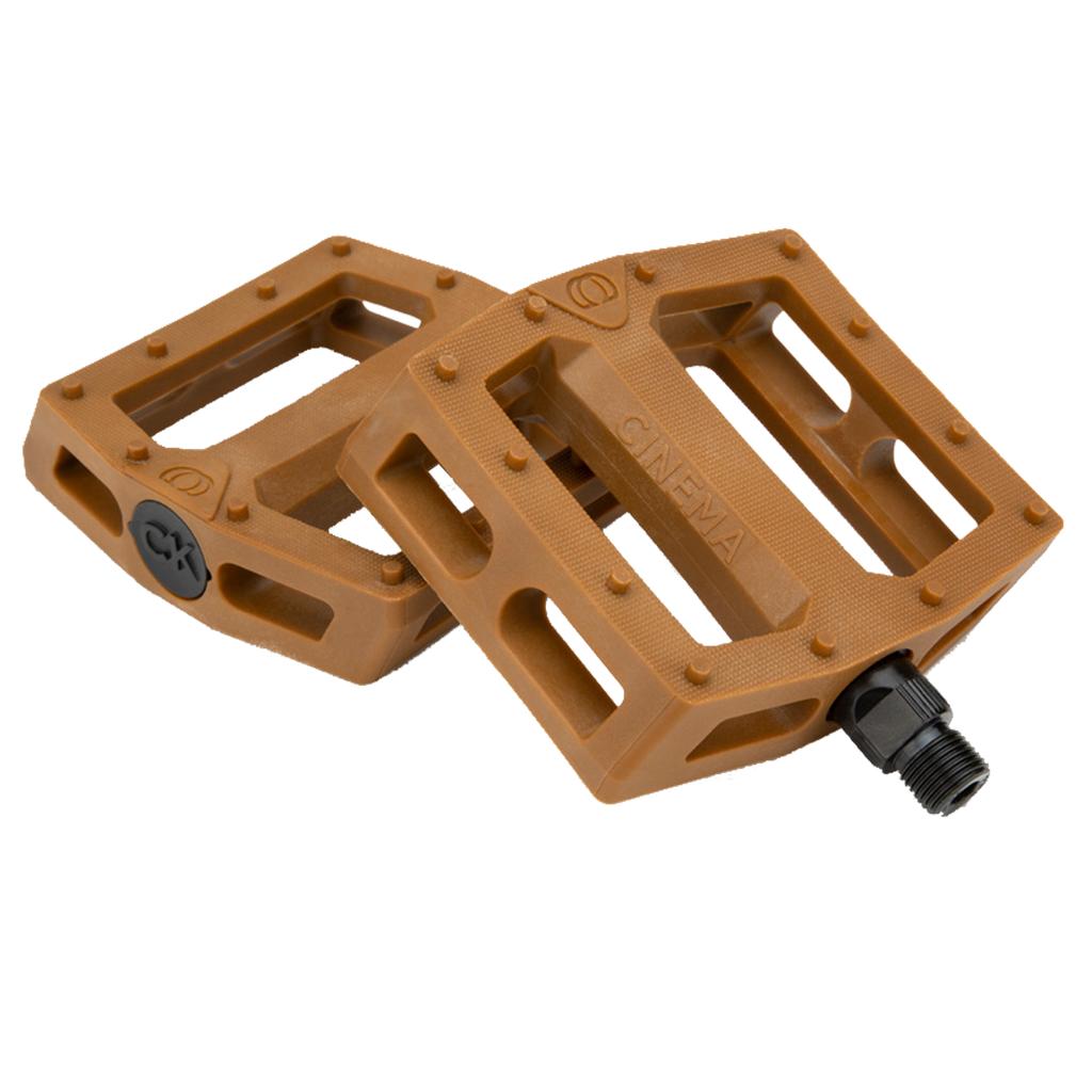 A pair of brown Cinema CK Pedals, featuring Chad Kerley’s signature rectangular design with a textured nylon/fiberglass blend surface and black axle ends, are displayed on a white background.