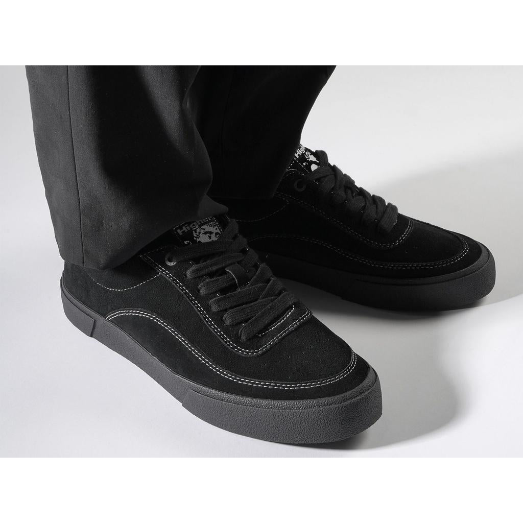 Person wearing Higher Crypt Suede Lace Up Shoes (Black/Black) with a suede upper and outsole grip pattern, paired with black pants on a white surface.