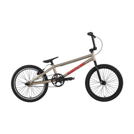 The Inspyre Neo Pro Cruiser Race Bike (2027), featuring a tan frame with red lettering, black tires, a black seat, and sealed hubs, is displayed against a plain white background. This entry-level race bike combines style and durability, making it an excellent choice for new riders.