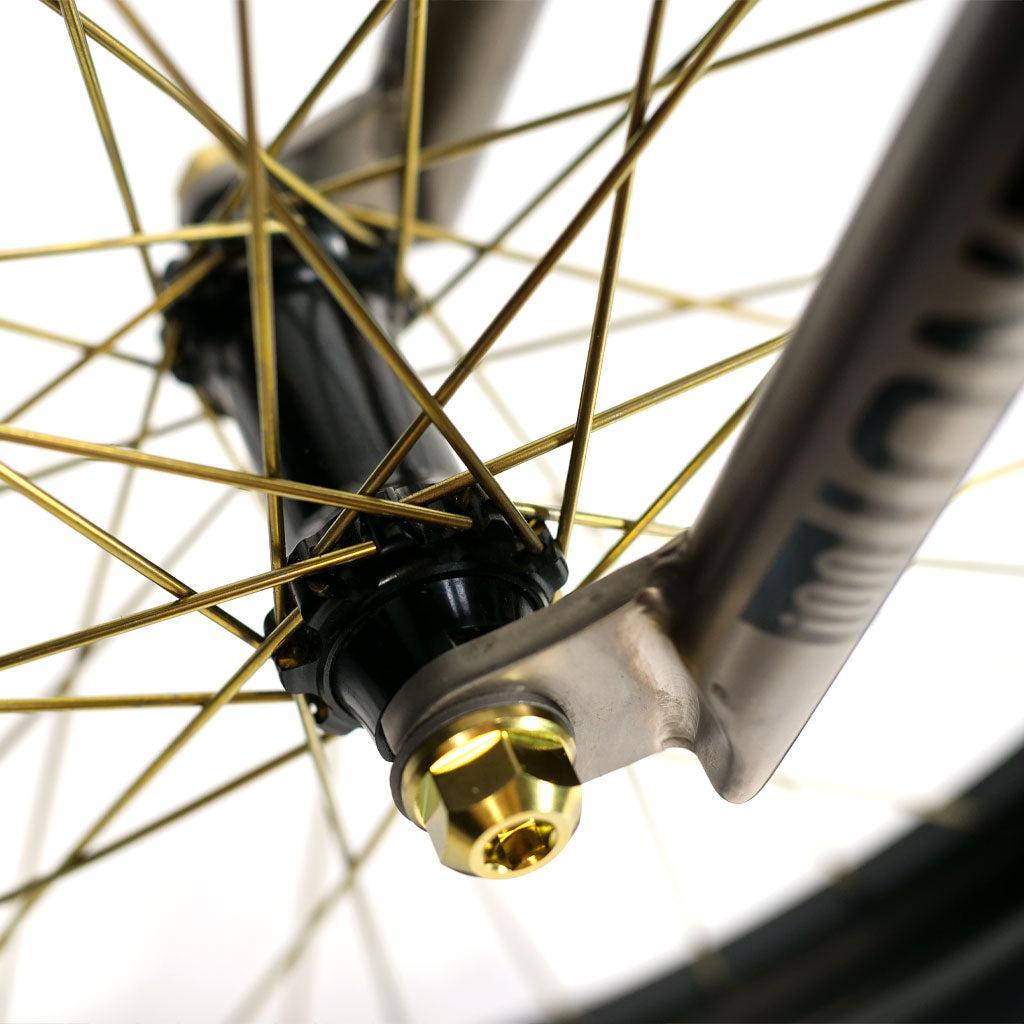 Close-up of an ION BMX TiXX 20 Inch Bike wheel featuring gold-colored Spectre straight pull hubs and a gold axle nut attached to a fork.