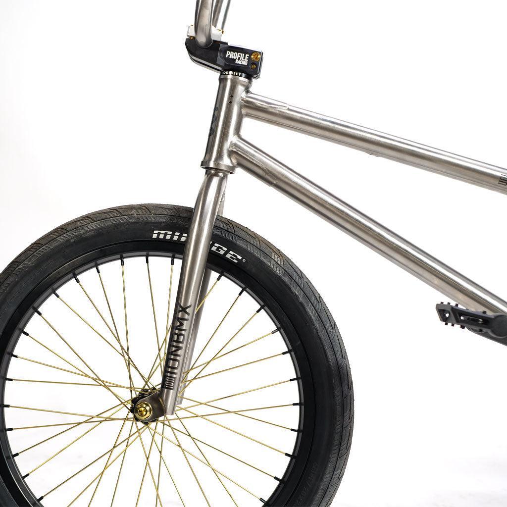 Close-up of an ION BMX TiXX 20 Inch Bike titanium frame with gold Spectre straight pull hub spokes and black tires.
