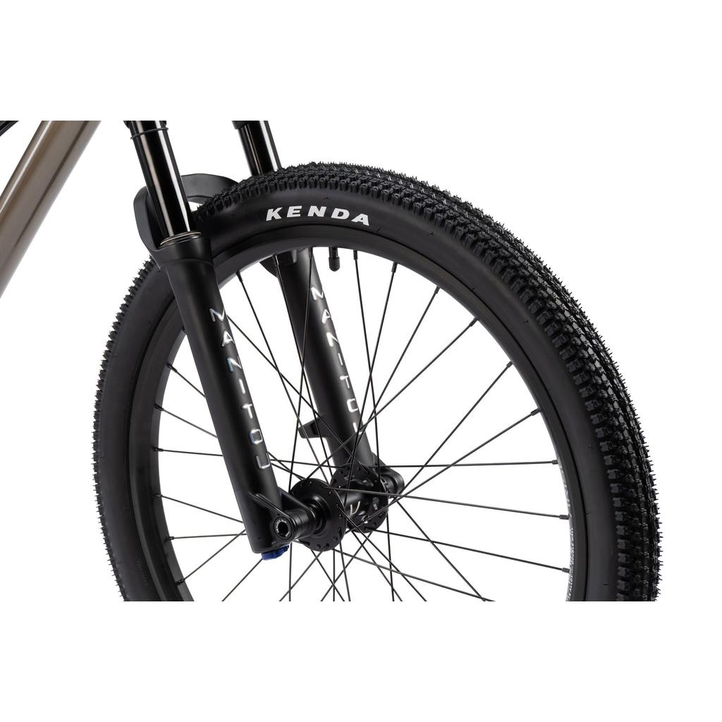 A close-up of the Radio Griffin 24 Inch Dirt Jumper Bike’s front wheel with a Kenda tire, Manitou suspension fork, and a 24” aluminum frame, set against a white background.