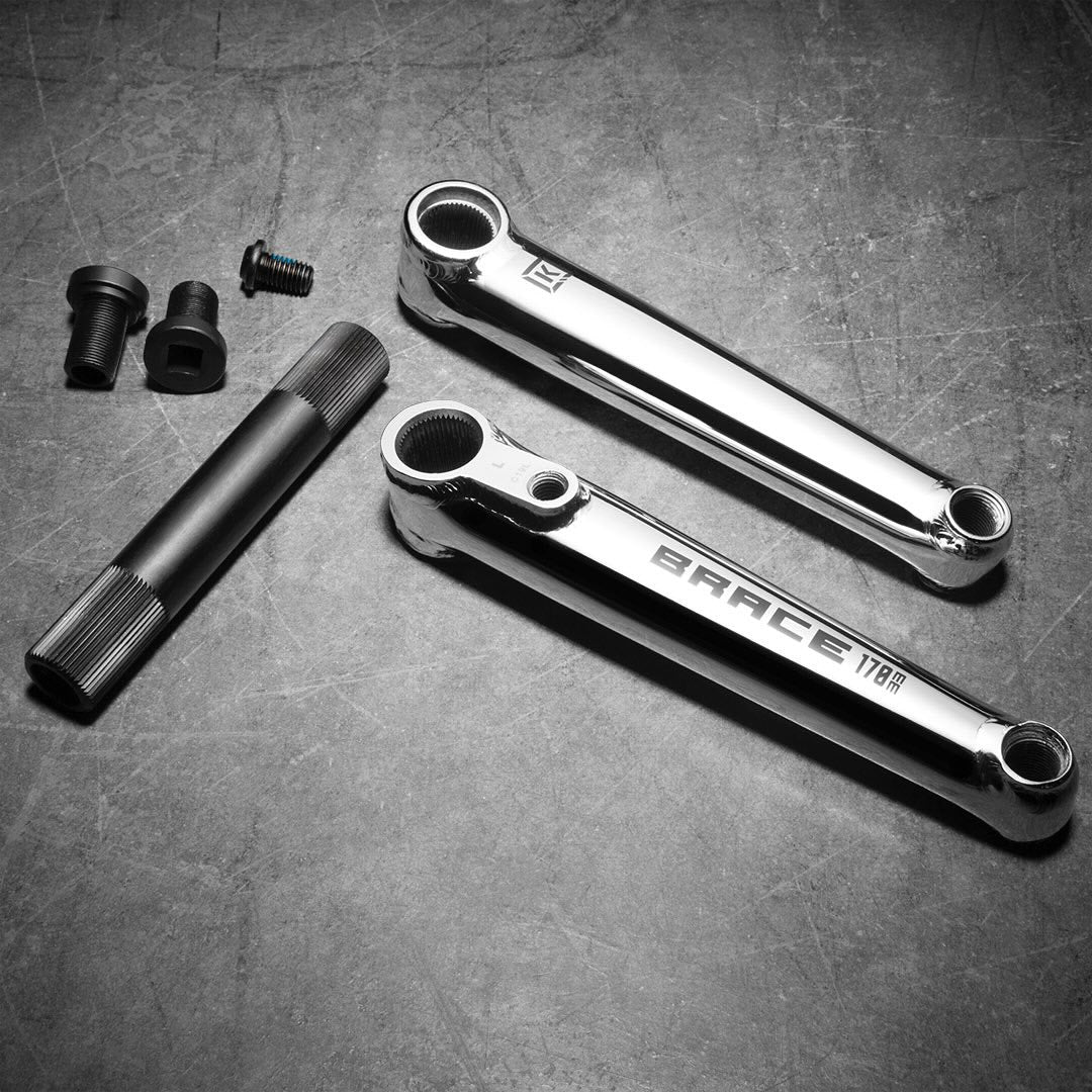 The Kink Brace Cranks have a 3-piece design, including crank arms, a 22mm hollow spindle, and small fittings on a textured surface.