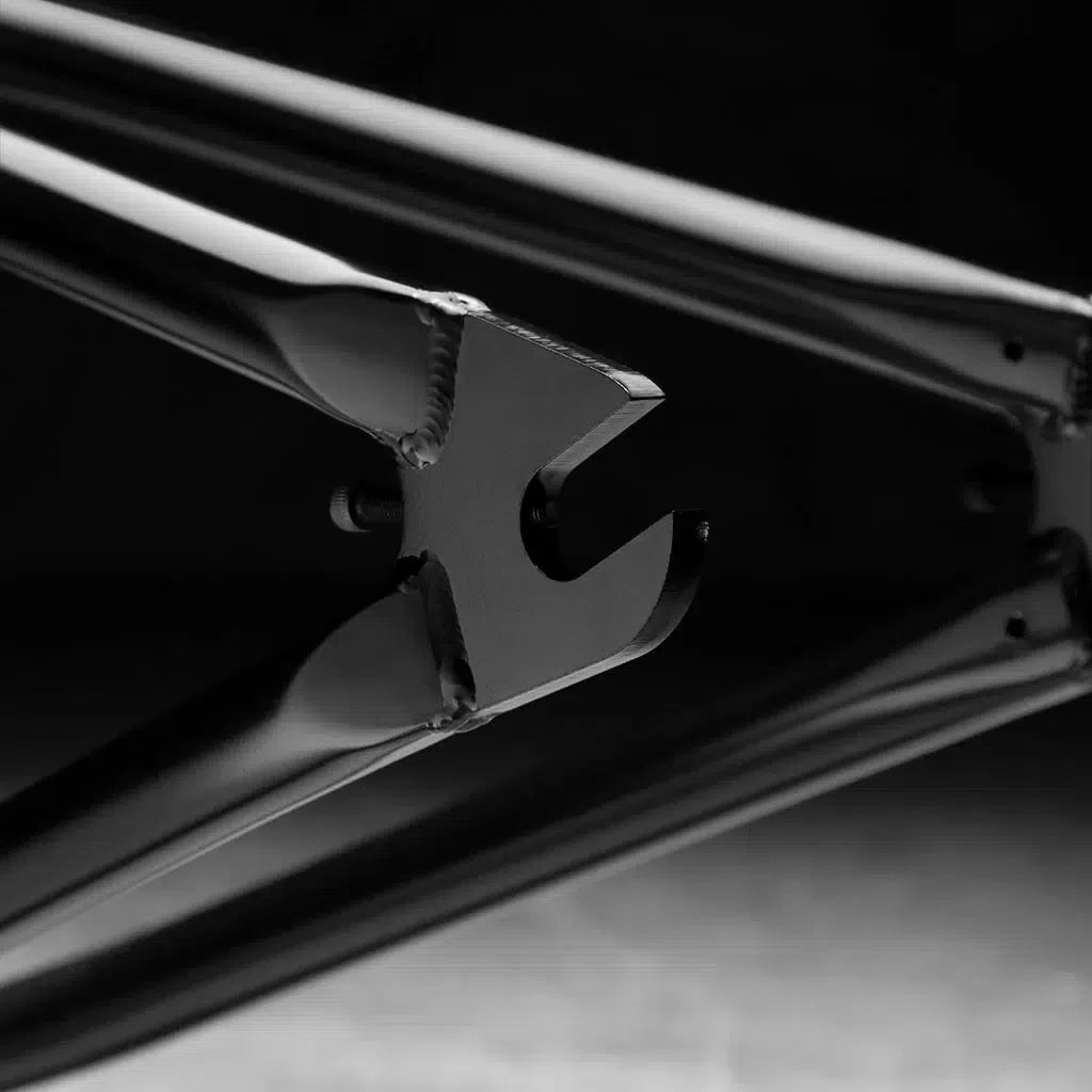 Close-up of the Kink Cloud Frame (Travis Hughes) dropout in black, featuring a sleek angular design made from 100% chromoly tubing, set against a dark background.