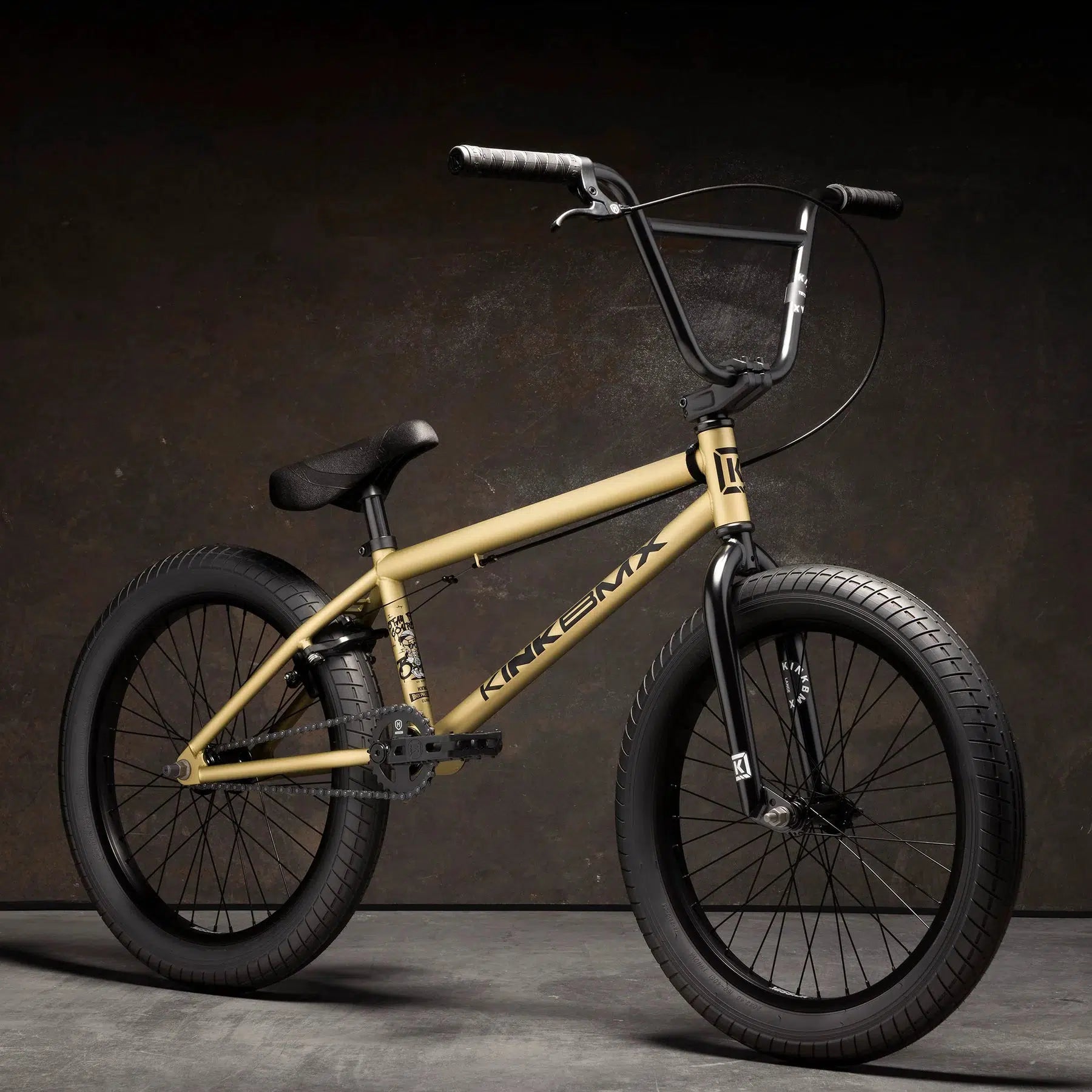 A beige Kink Curb 20 Inch Bike with modern geometry features, including black handlebars, seat, and Mission Tracker Tyres, set against a dark background.