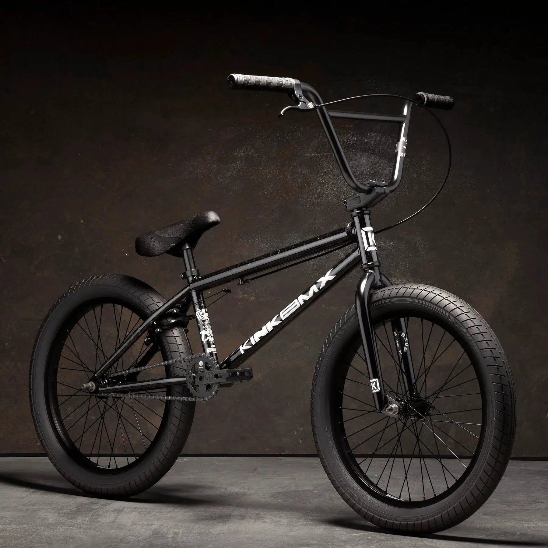 The Kink Curb 20 Inch Bike, available in black, is equipped with Mission Tracker Tyres and a sturdy frame. It features Kink Ace Grips for ultimate control, all showcased against a dark background.