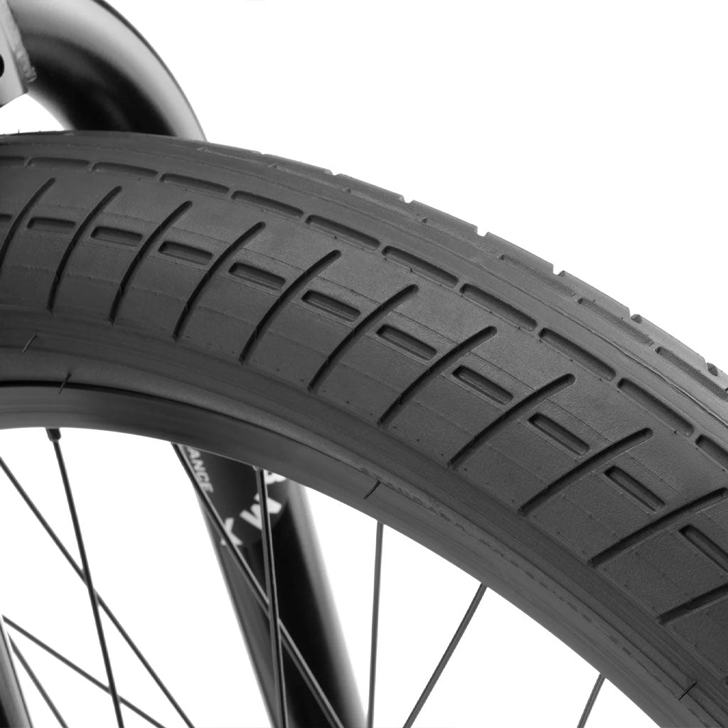 Close-up of a 20 inch bike wheel focusing on the black tire tread and spokes. The image captures the details of the tire's pattern and the structure of this Kink Curb 20 Inch Bike's wheel.