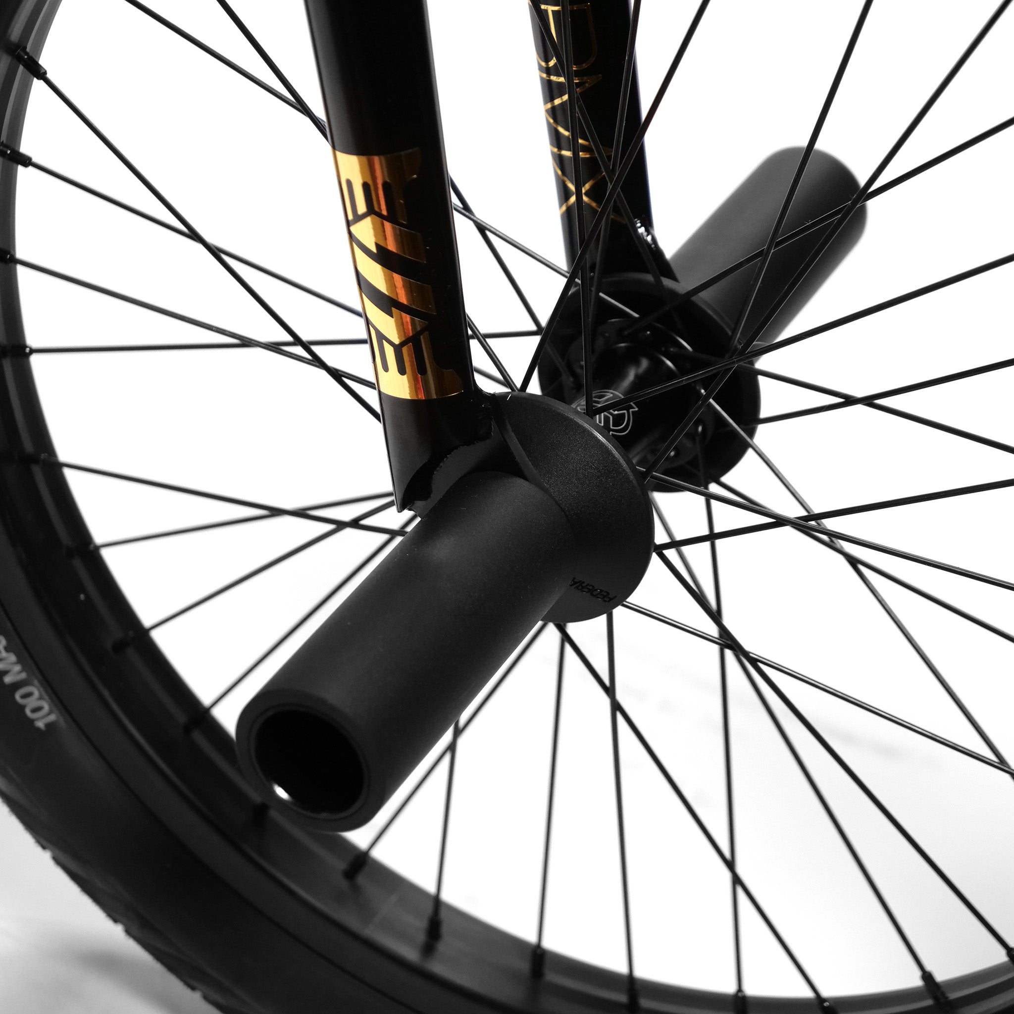 Close-up of a black bicycle wheel with gold detailing, showing the spokes, hub, and a peg attached to the axle—a stunning highlight from a Kink Tactic Custom 20 Inch Bike.