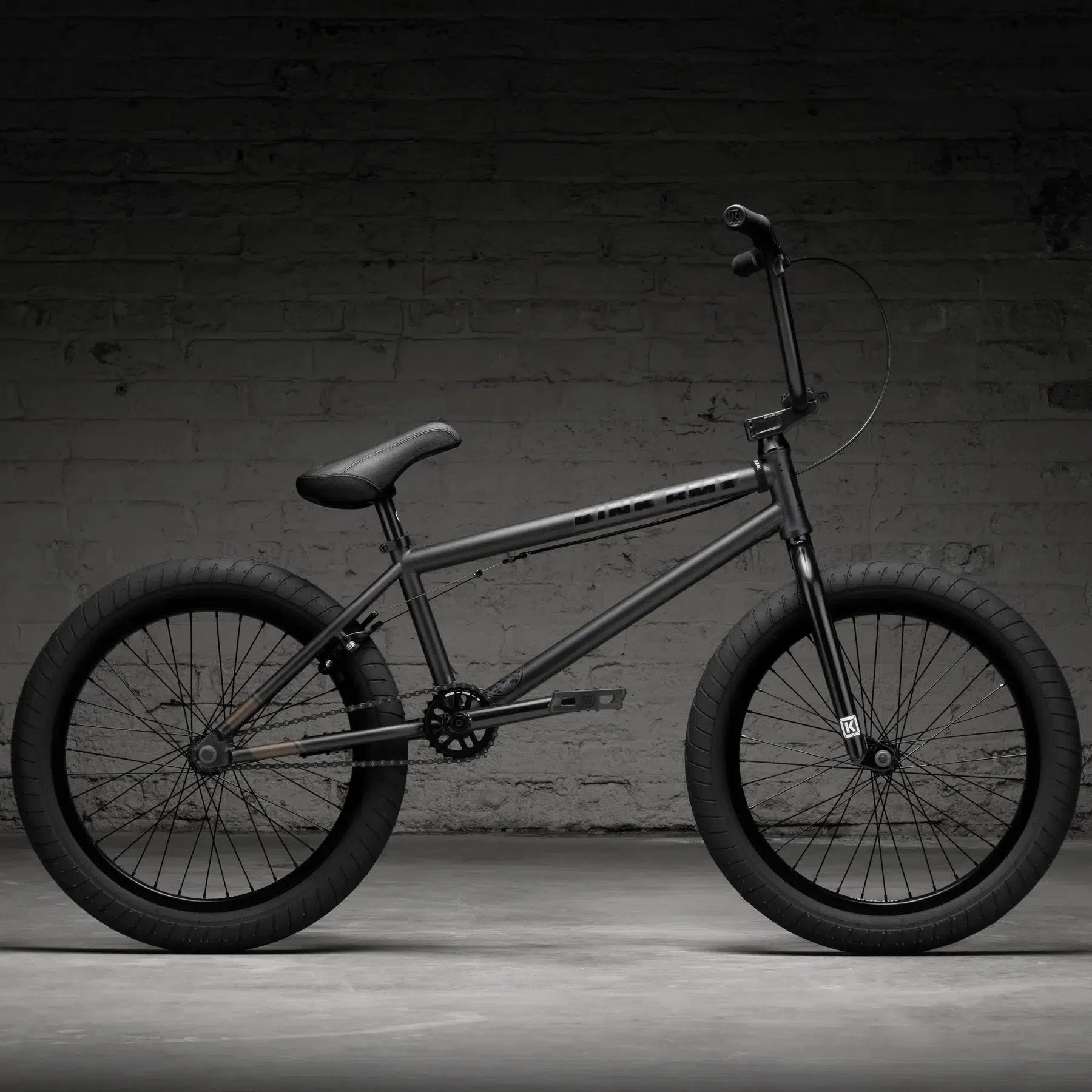 The Kink Whip 20 Inch Bike (2026) features a robust 4130 Chromoly frame and thick tires, showcased against a dark brick wall, offering durable and thrilling rides.
