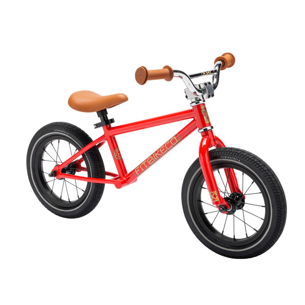 The Fit Misfit 12 Inch Balance Bike for kids features a red steel frame, black wheels, brown seat, and matching brown handlebar grips, shown on a white background.