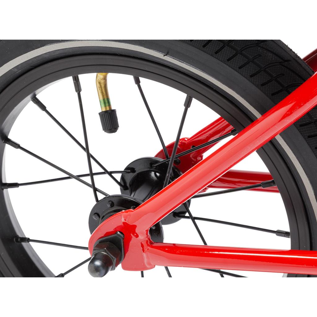Close-up of the Fit Misfit 12 Inch Balance Bike wheel, showing a black tire, metal spokes, visible valve stem, and red TIG welded steel frame.