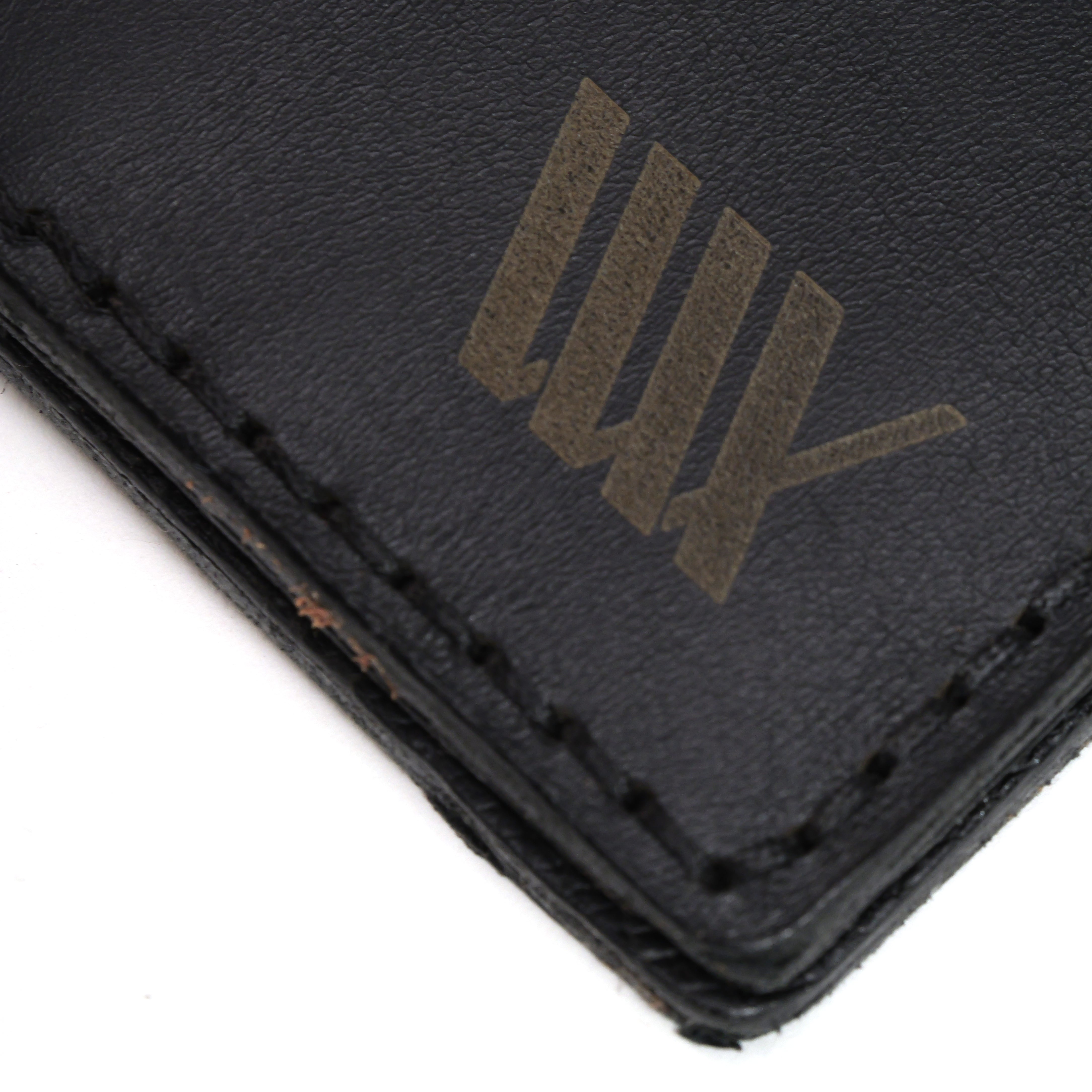 Close-up of a black full-grain leather LUXBMX Bifold Wallet corner with visible stitching and gold "UNDFTD" tally mark logo, handcrafted in Queensland.