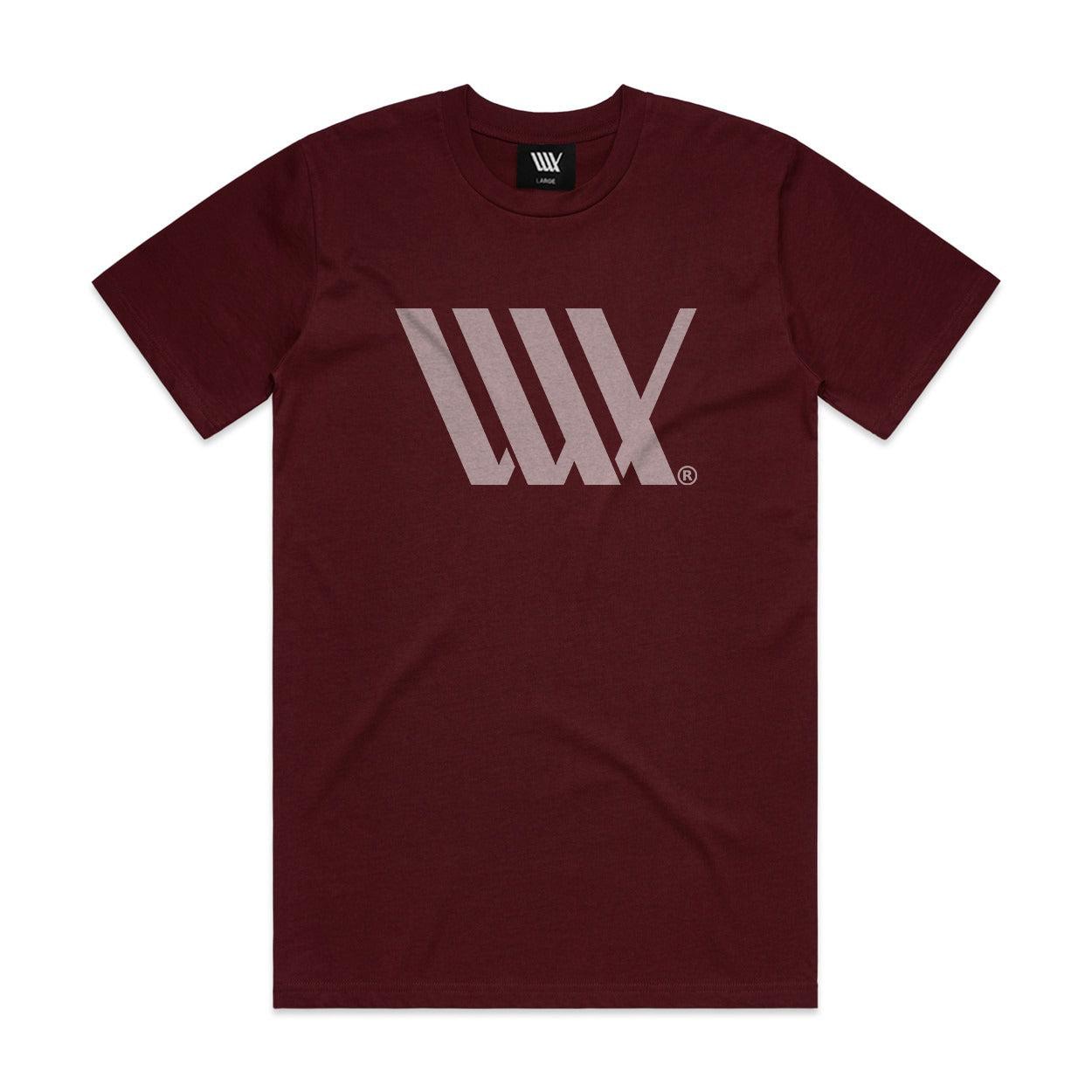 The LUXBMX Flag Tee Maroon is a heavyweight t-shirt with a light gray geometric logo on the chest, featuring overlapping lines forming an angular design.