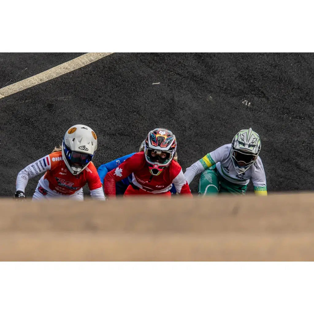 Capture dynamic race action with LUXBMX Race Photo Packages – Lake Macquarie National Series May 2025: three BMX cyclists in full gear line up on the track, viewed from above and partially hidden by a ramp.