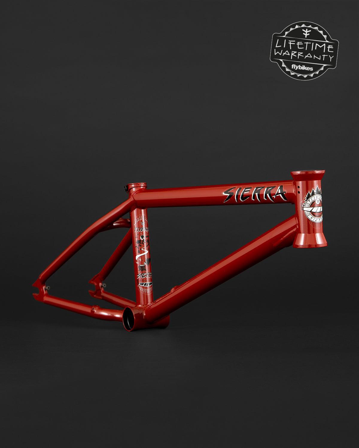 The Fly Bikes Sierra 18" Frame, sporting "Sierra" branding on a dark background, boasts a sleek design. With a "Lifetime Warranty" label at the top right, it offers assurance in this premium build inspired by Sergio Layos' signature style.