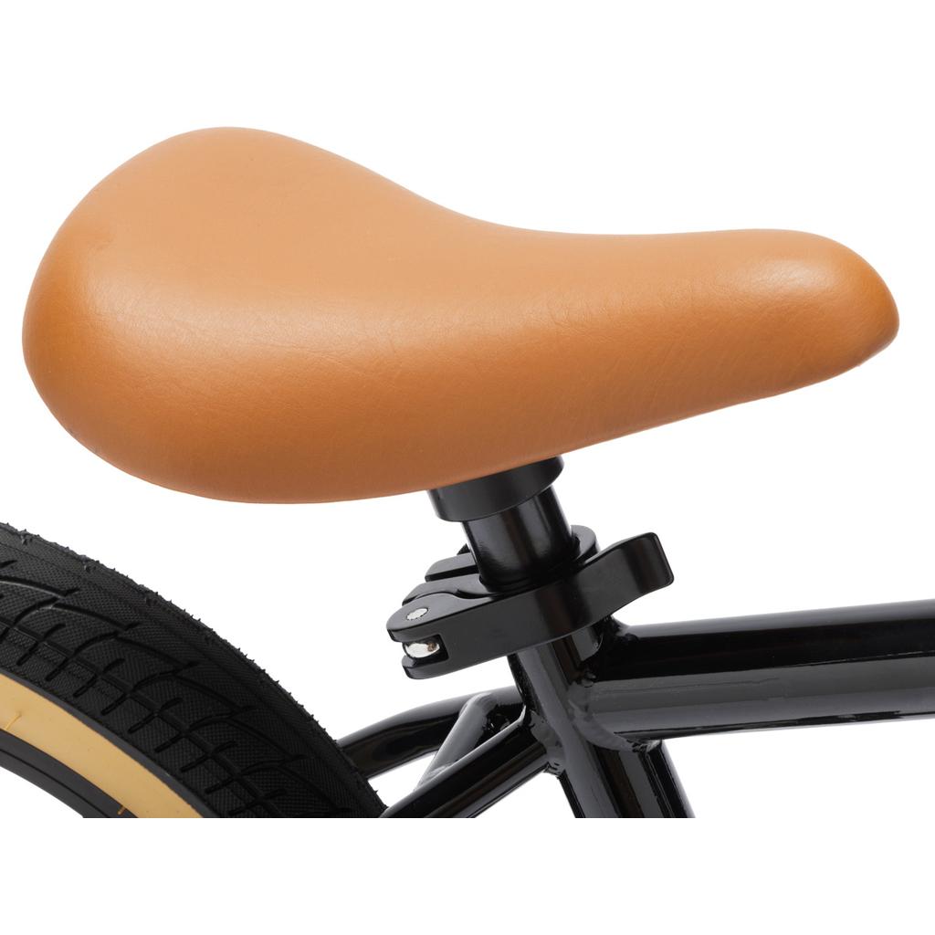 Close-up of a tan seat on the Fit Misfit 12 Inch Balance Bike's black TIG welded steel frame, with part of the rear wheel shown—perfect for young BMX fans who value quality and style in their balance bike.