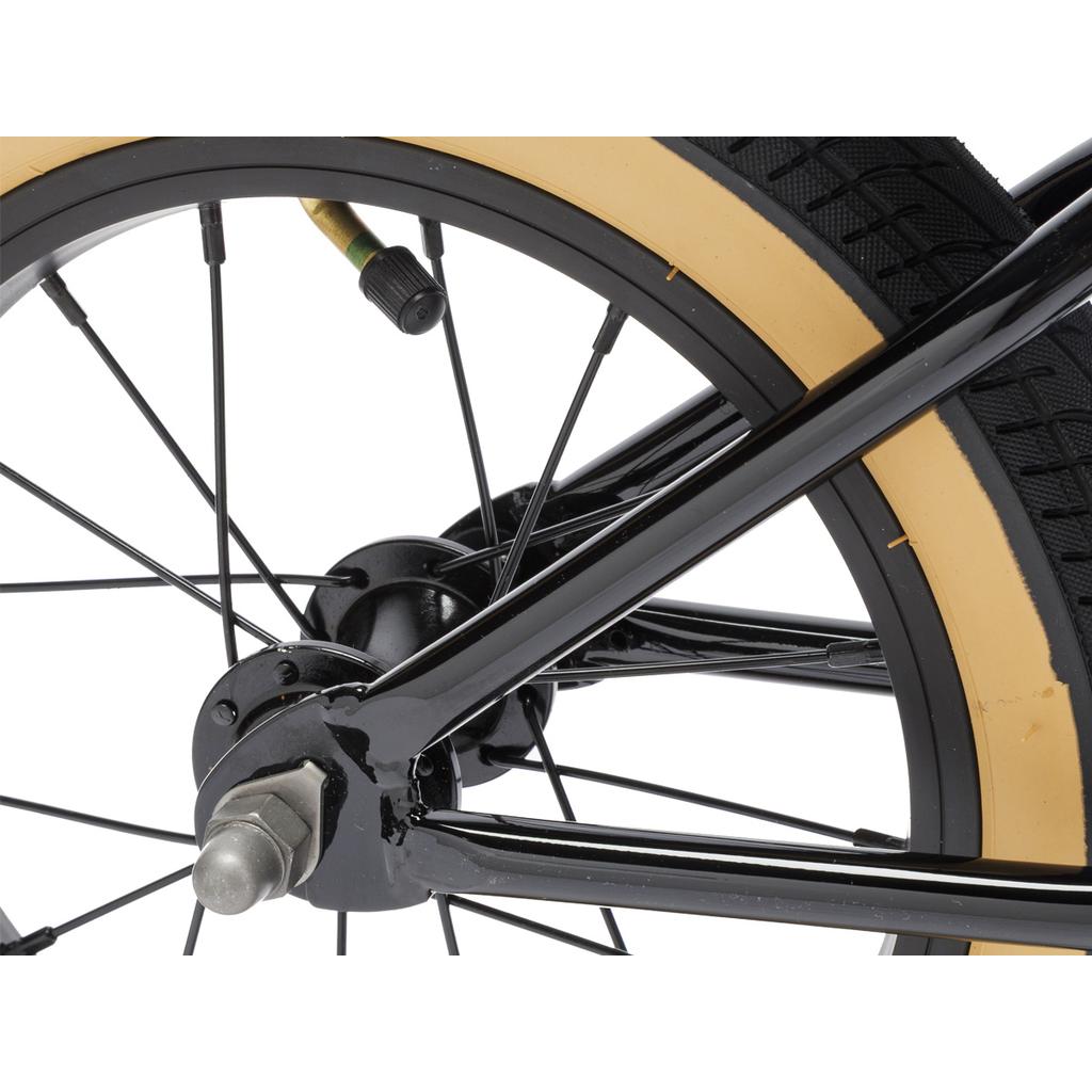 Close-up of a Fit Misfit 12 Inch Balance Bike wheel, featuring a tan sidewall tire, metal spokes, axle nut, and air valve.