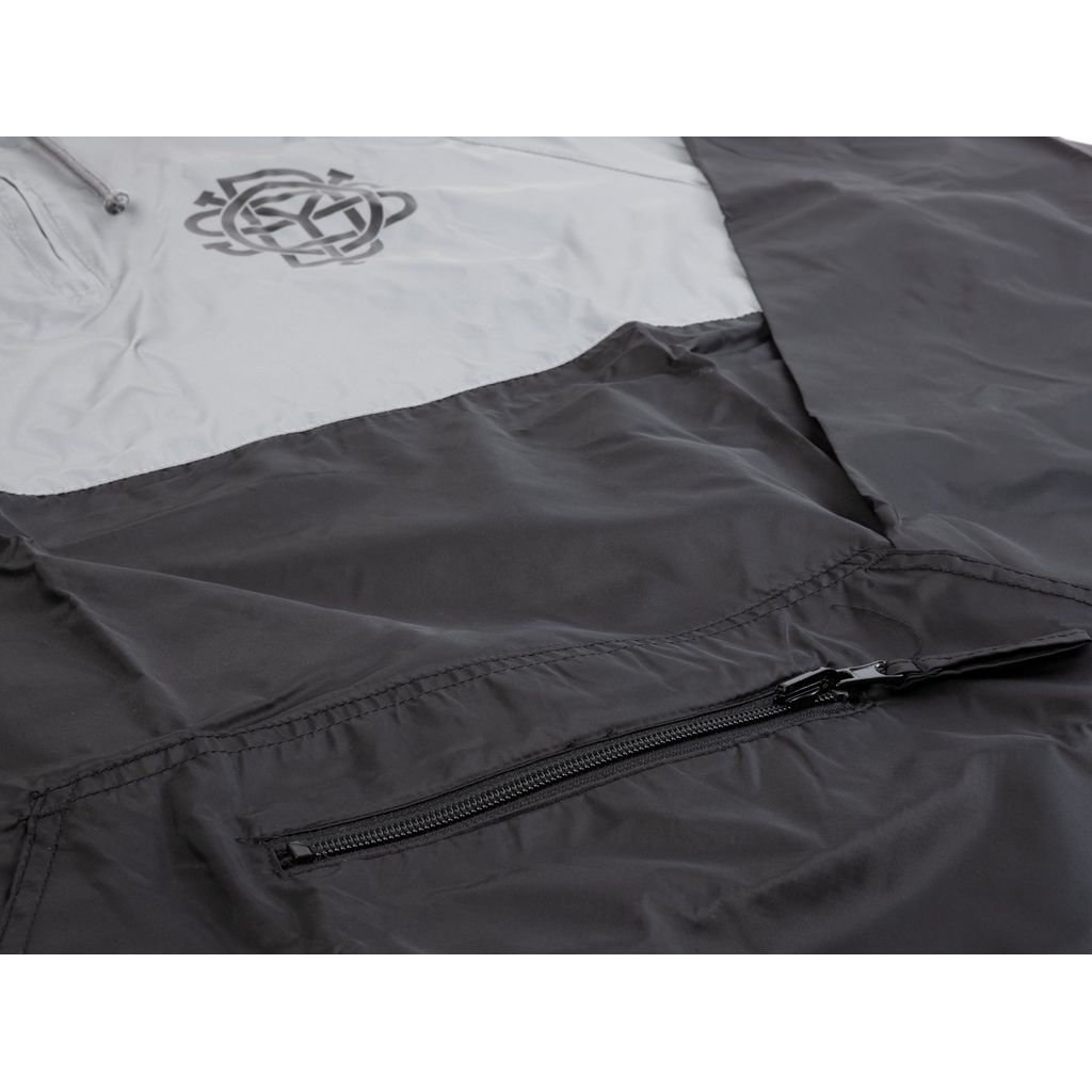 Close-up of the Odyssey Monogram Windbreaker, a black and gray, water-resistant jacket featuring a zippered pocket and a geometric logo on the upper left side.