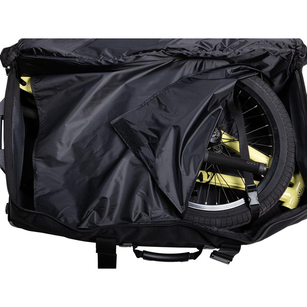 A partially unzipped Odyssey Traveler Pro Bike Bag in black holds a folded yellow bicycle, with its front wheel and handlebar visible.