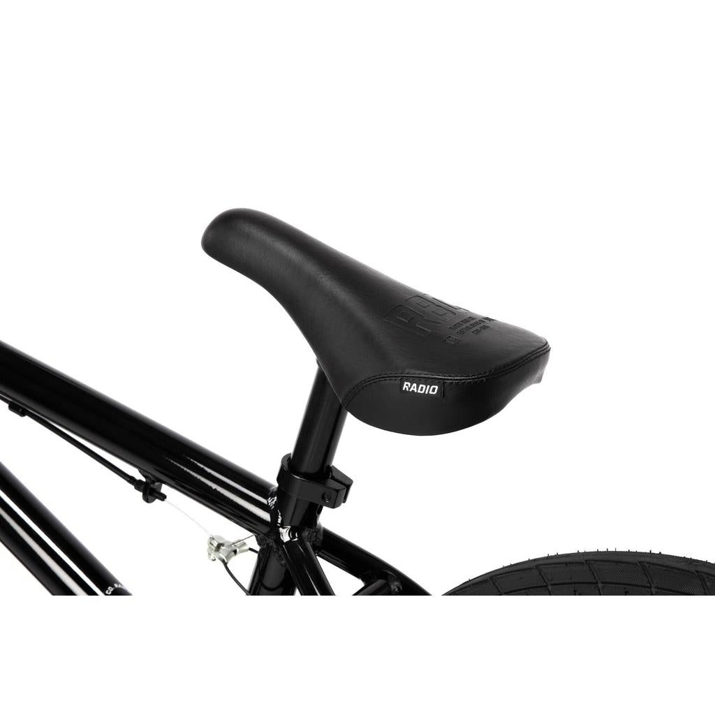 Close-up of the black "RADIO" seat mounted on the seat post of the Radio Dice 18 Inch Bike, featuring part of the frame and Salt Tracer Tyres, set against a white background.