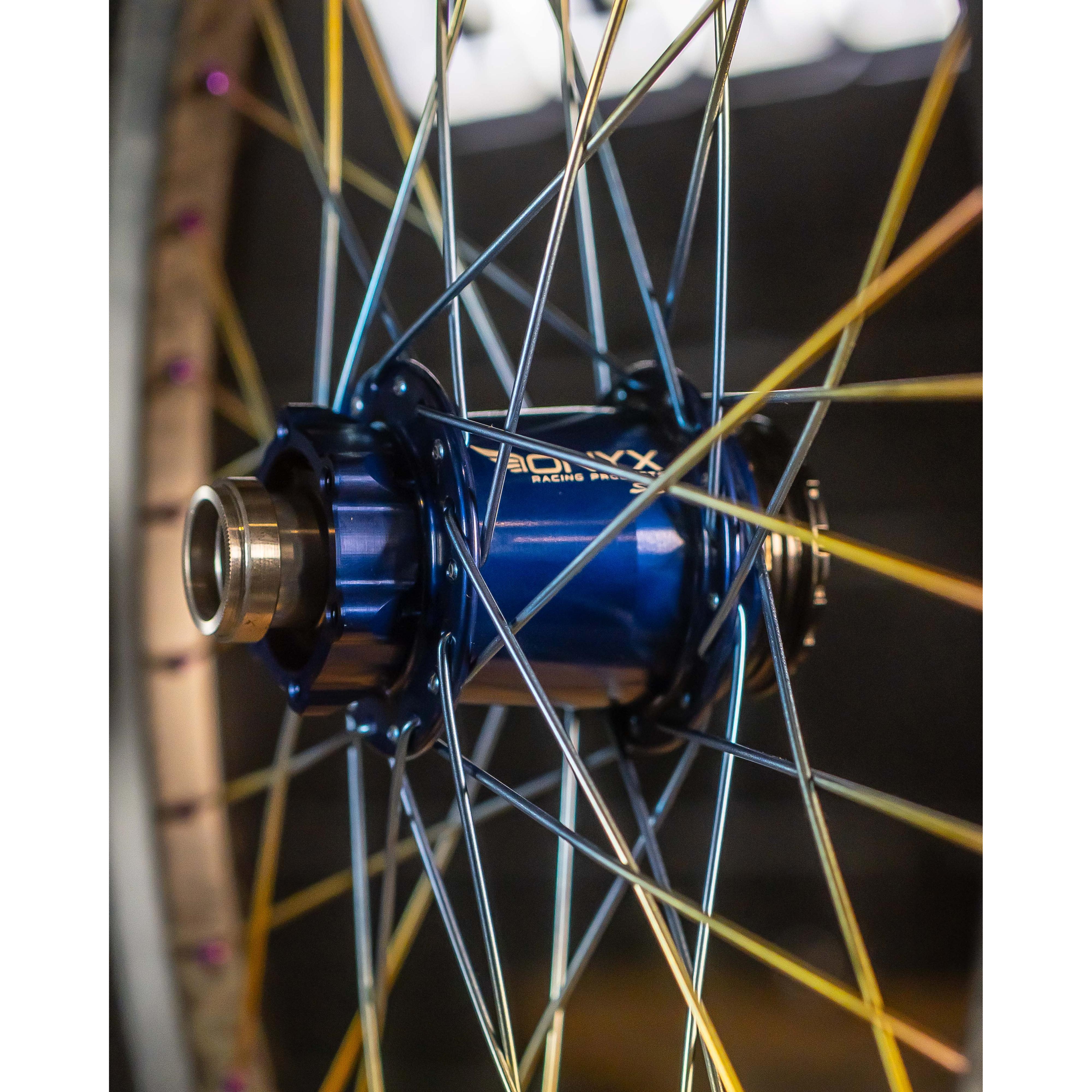 Close-up of Onyx X Spectre Carbon Marble Sunset 20 Inch Wheelset, highlighting titanium spokes and metallic components against a blurred background.