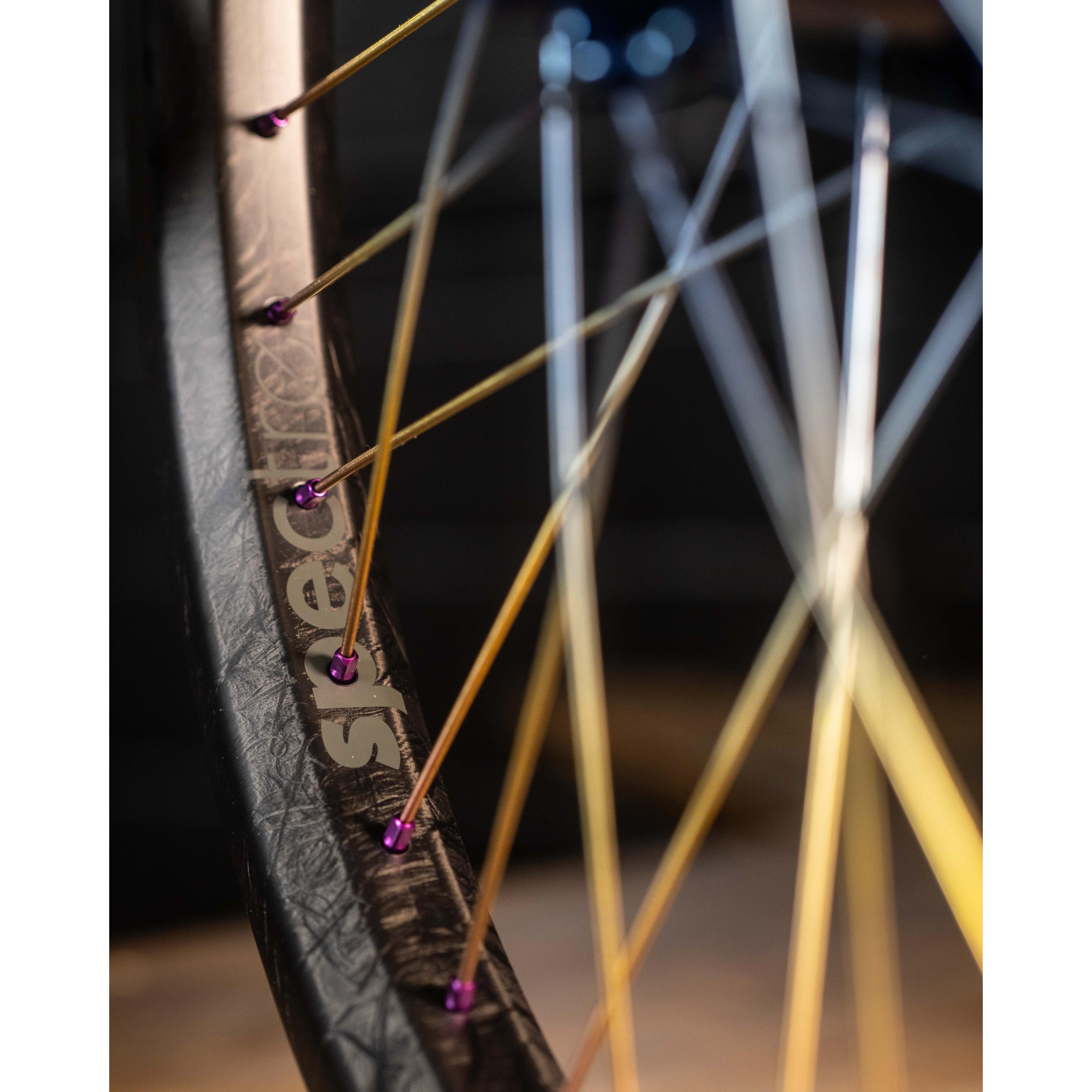 Close-up of an Onyx X Spectre Carbon Marble Sunset 20-inch wheelset, highlighting colorful spokes on a sleek black rim with premium Toray T800 carbon fiber and the "spectre" brand name.