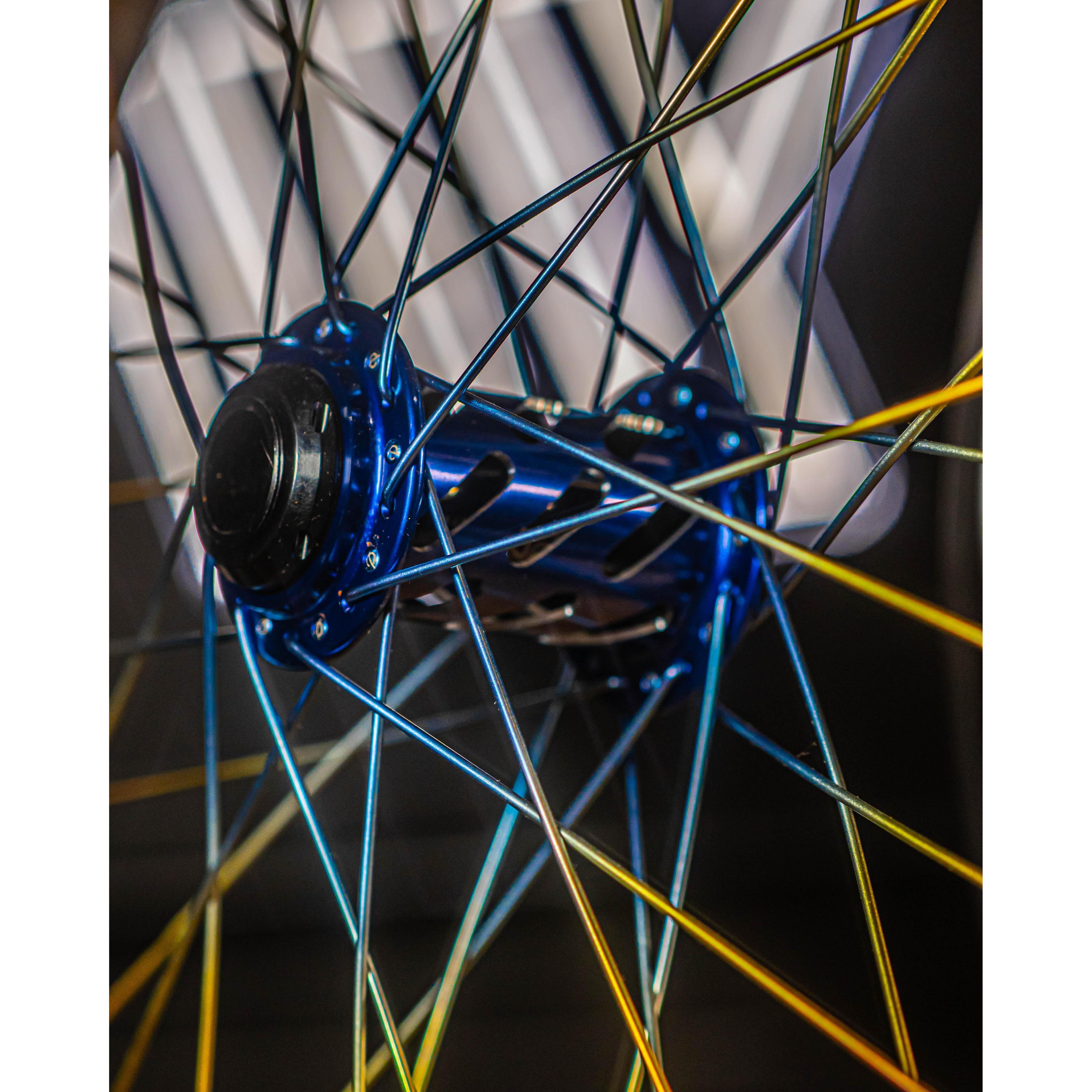 Close-up of an Onyx X Spectre Carbon Marble Sunset wheel hub with iridescent spokes and Toray T800 carbon fiber rims, set against a blurred background.