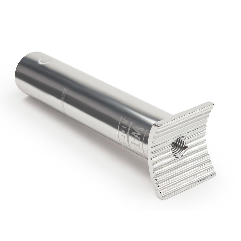The Wethepeople Pivotal Socket Seatpost is a silver metal seat post with a fluted, flat top and central hex insert, shown on a white background.