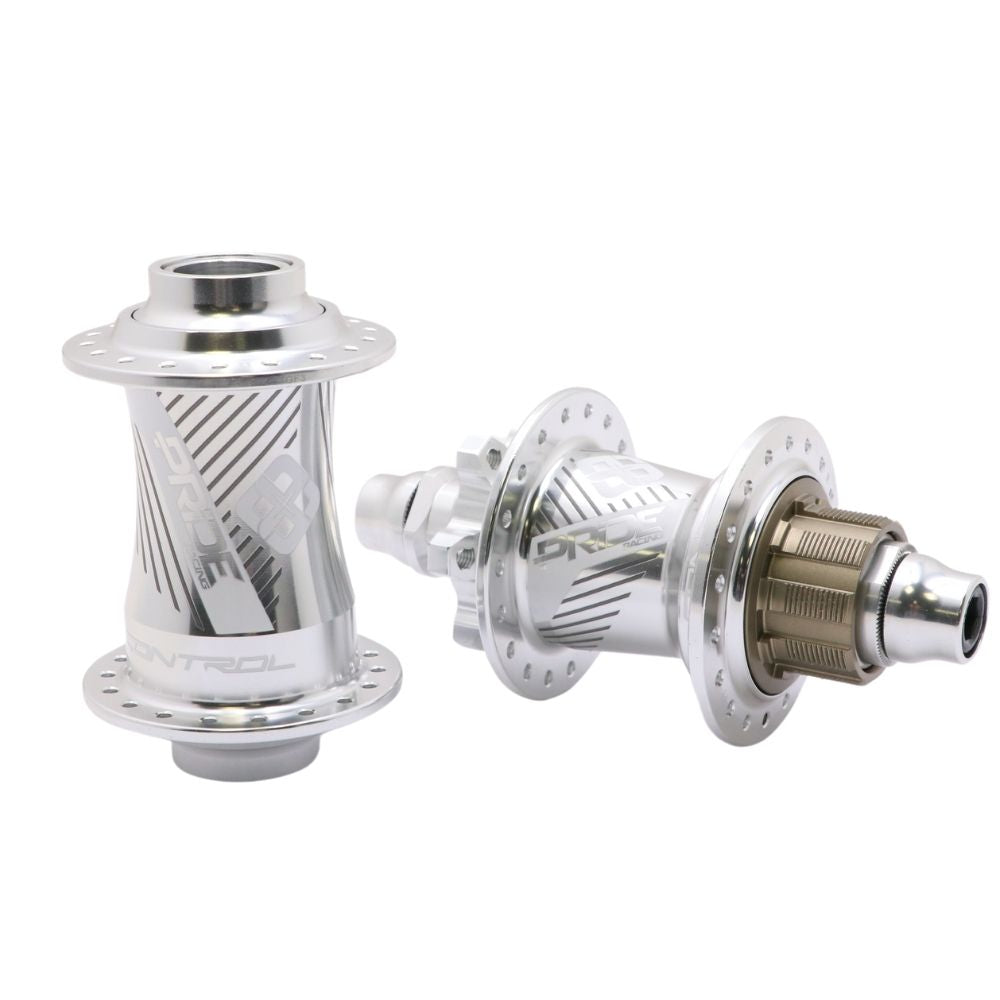 The Pride Control V2 Pro 36H 10mm Hubset includes two CNC machined silver bicycle hubs featuring engraved patterns; one front hub and a rear hub equipped with a cassette body. These expertly crafted components are ideal for BMX racing, offering a perfect combination of durability and precision.