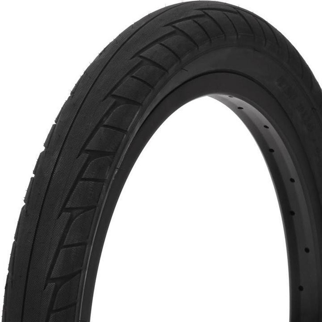 Close-up of a single black bicycle tire with a smooth tread pattern and visible sidewall markings, perfect for city streets. This Primo 555C Tyre offers superior grip, ensuring a safe and comfortable ride.