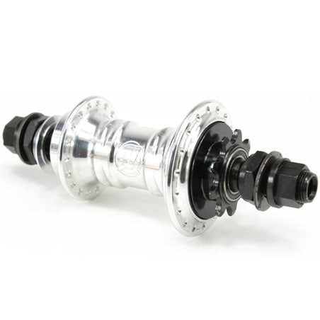 The Profile Mini Rear Cassette Hub is a sleek metal rear hub with a low-flange design, complete with black threaded axle nuts and a sprocket on one side—ideal for BMX enthusiasts.