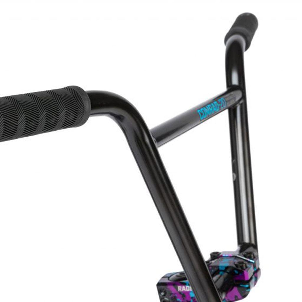 Close-up of black BMX handlebars with textured grips and a colorful stem, showcasing the Salt Parts on the Radio Comrad 20 inch Bike.