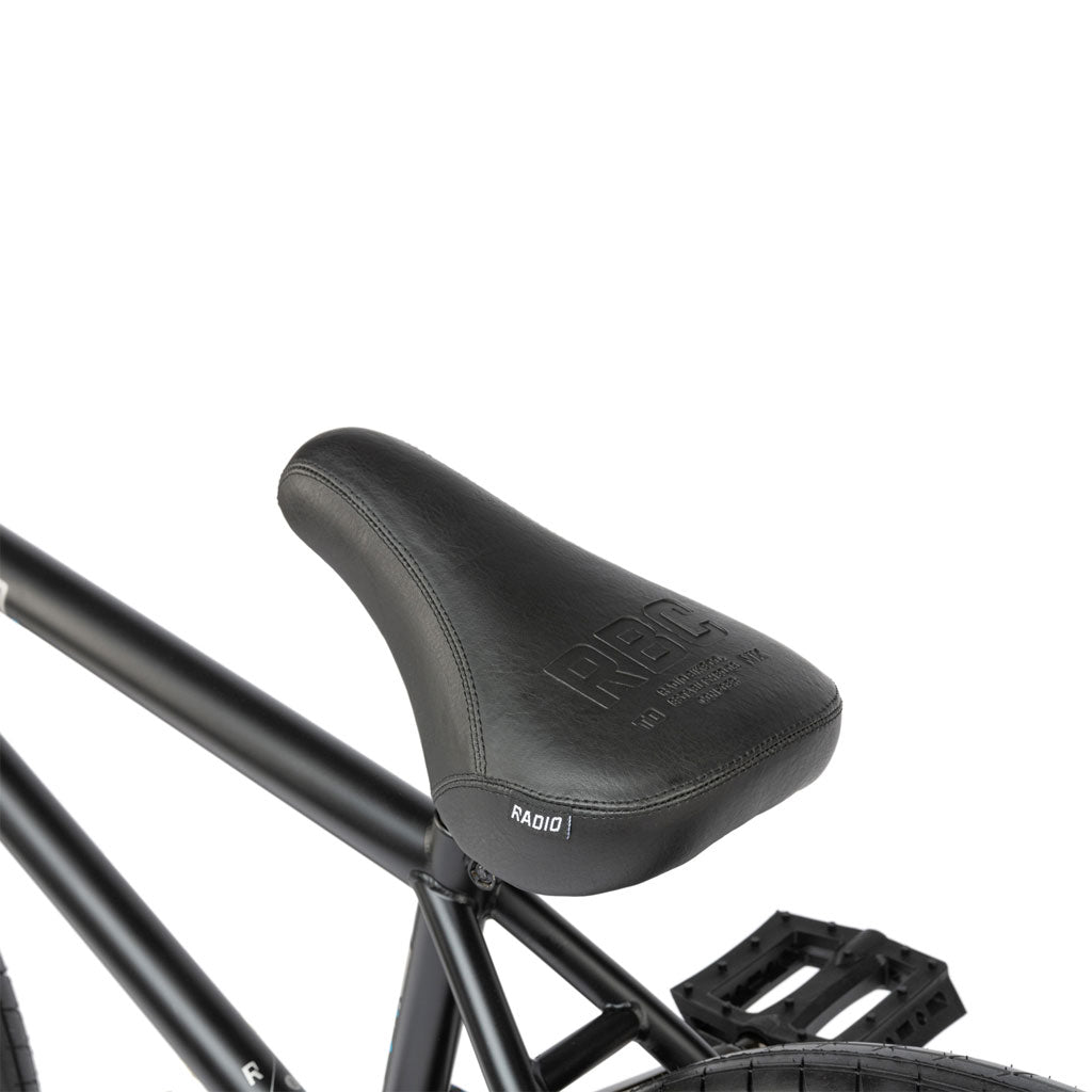 Close-up of a black bicycle seat attached to the sleek full cromoly frame of a Radio Comrad 20 inch Bike, with "Radio" visible on the seat.
