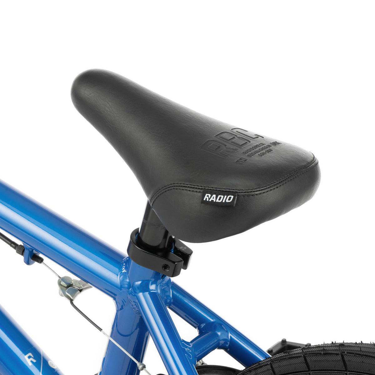 Black bicycle saddle labeled "Radio" attached to a metallic blue Radio Dice 16 Inch Bike frame, partially visible with a portion of the rear tire.
