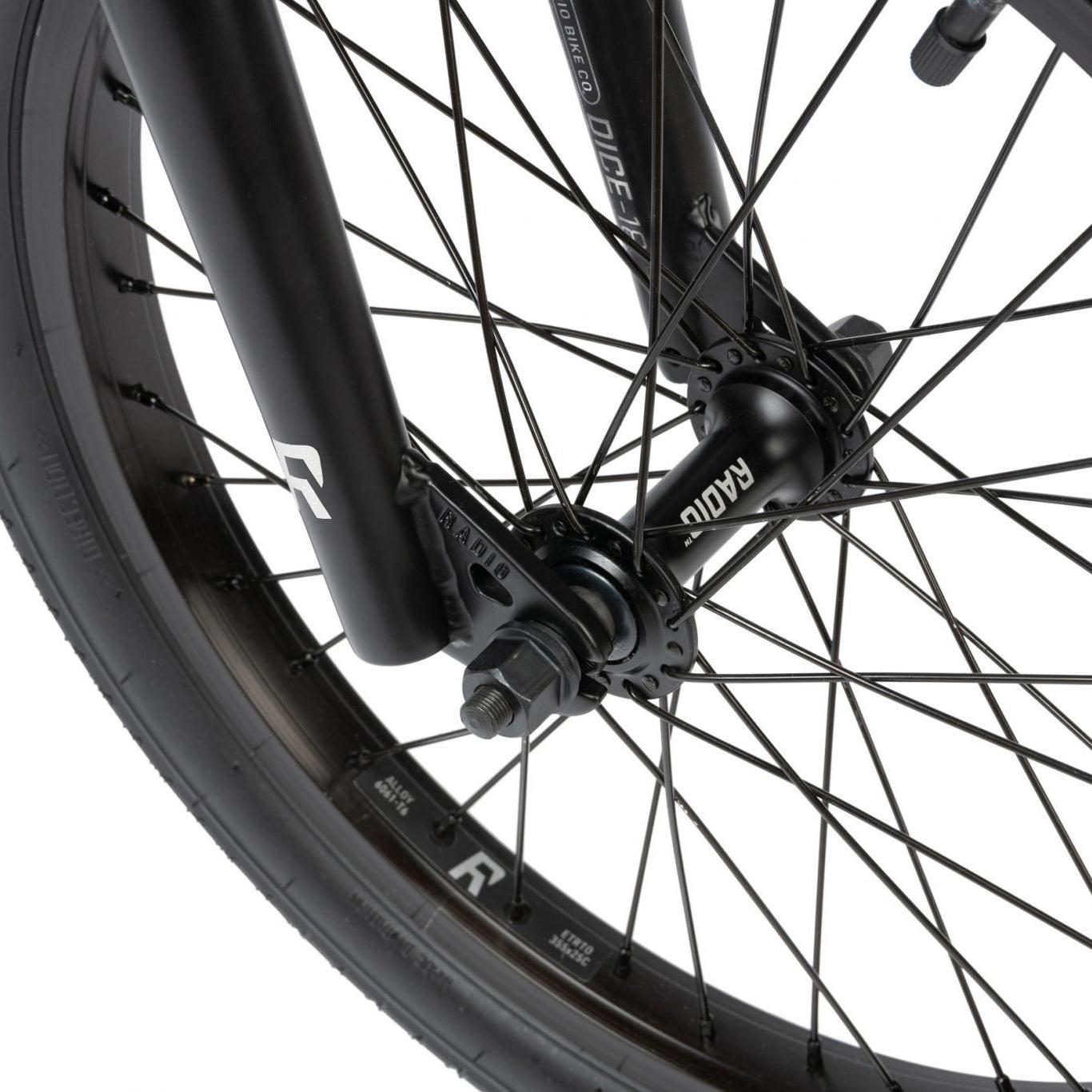 Close-up of a bicycle wheel showing the spokes, hub labeled "RADIO," and part of the fork. The tire branding "INNOVA" and other small details are visible, hinting at the high-quality components typically seen on models like the Radio Dice 18 Inch Bike.