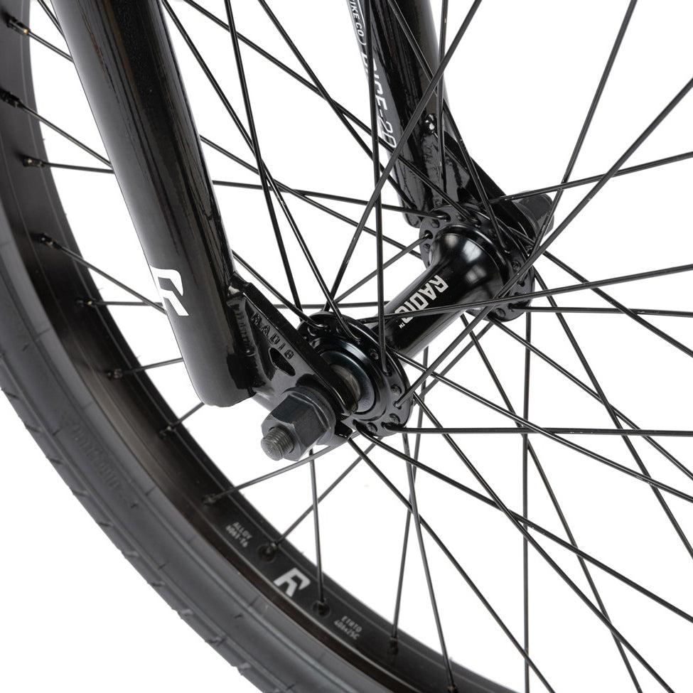 Close-up view of a black bicycle wheel with spokes and a visible axle, featuring the Radio Dice 20 Inch Bike.