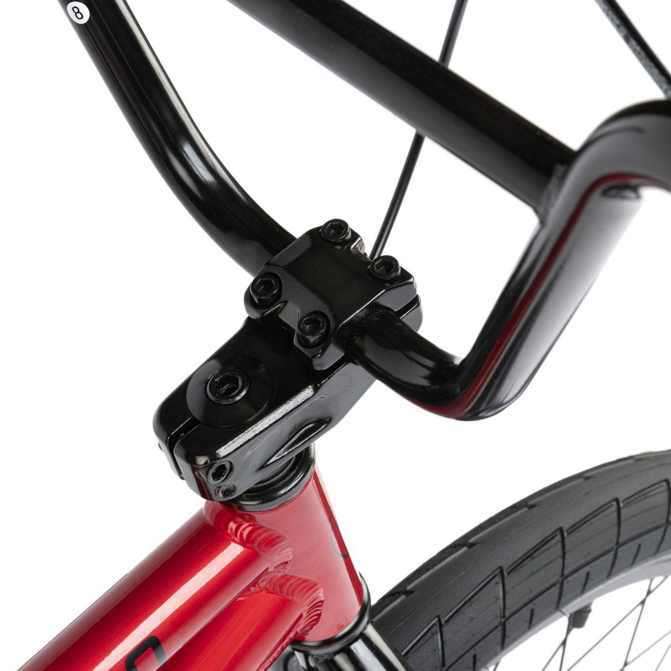 Close-up of a black and red Radio Dice 20 Inch Bike handlebar and stem assembly, featuring the front part of the 6061 Alloy frame and part of the front wheel with Salt Tracer Tyres.