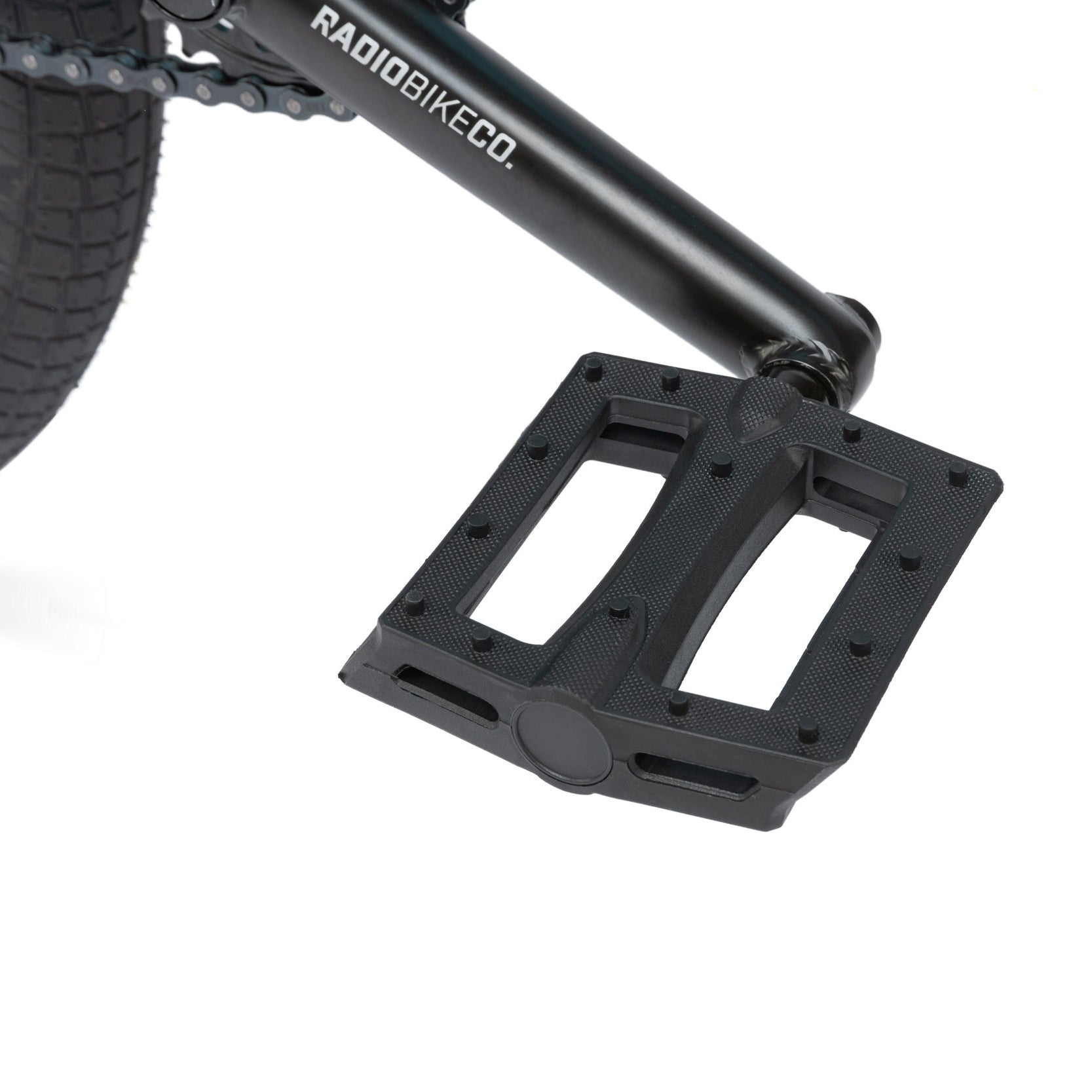 Close-up of a black bicycle pedal attached to the crank arm, with the brand name "Radiobikeco." visible on the arm. Perfect for beginner riders, this is part of the high-quality bike parts found on the Radio Evol 20 Inch Bike.