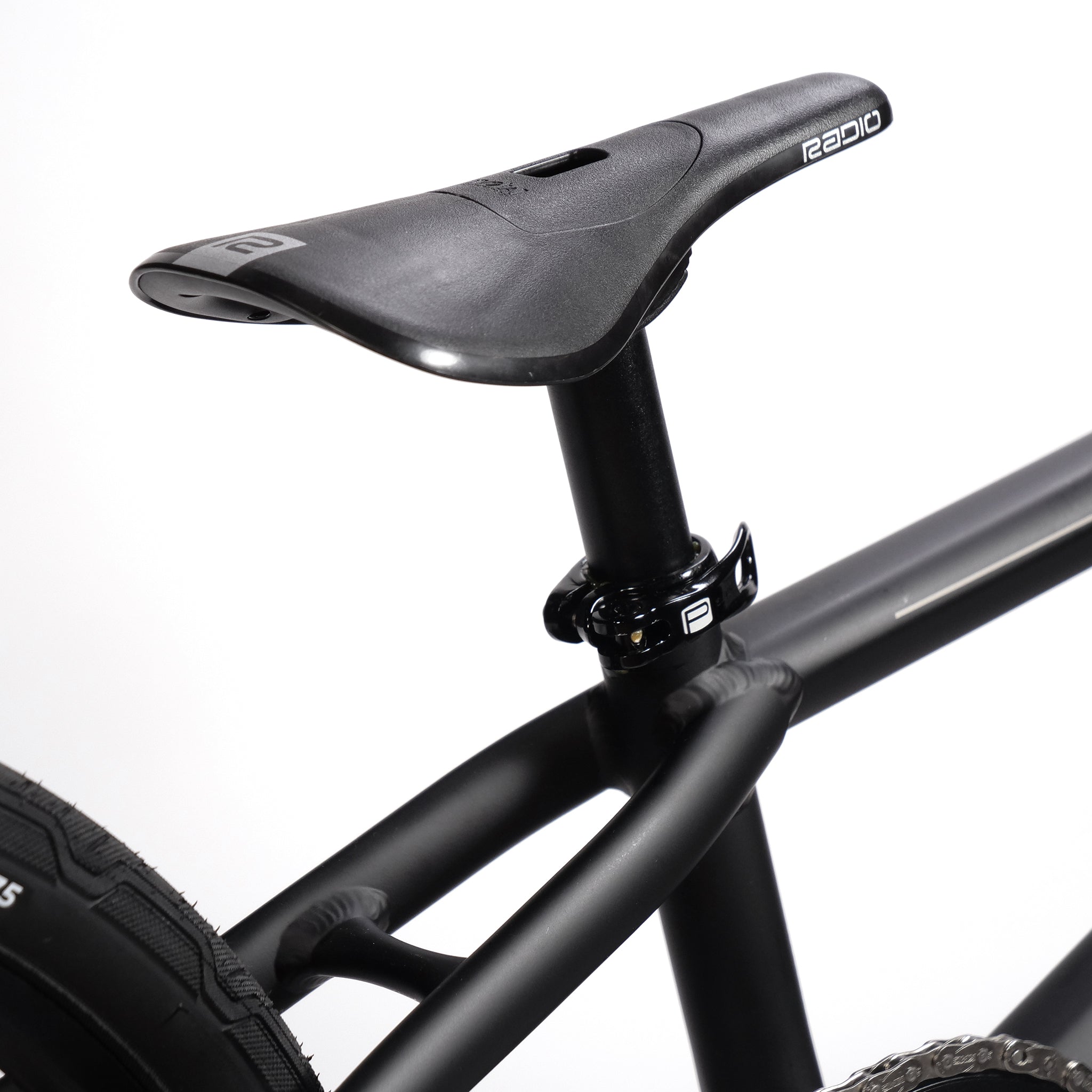 Close-up of a black bicycle seat on the lightweight hydro-formed frame of the Radio Quartz Pro XL Bike 2025, with visible parts of the seat post, rear wheel, and hydraulic disc brakes.
