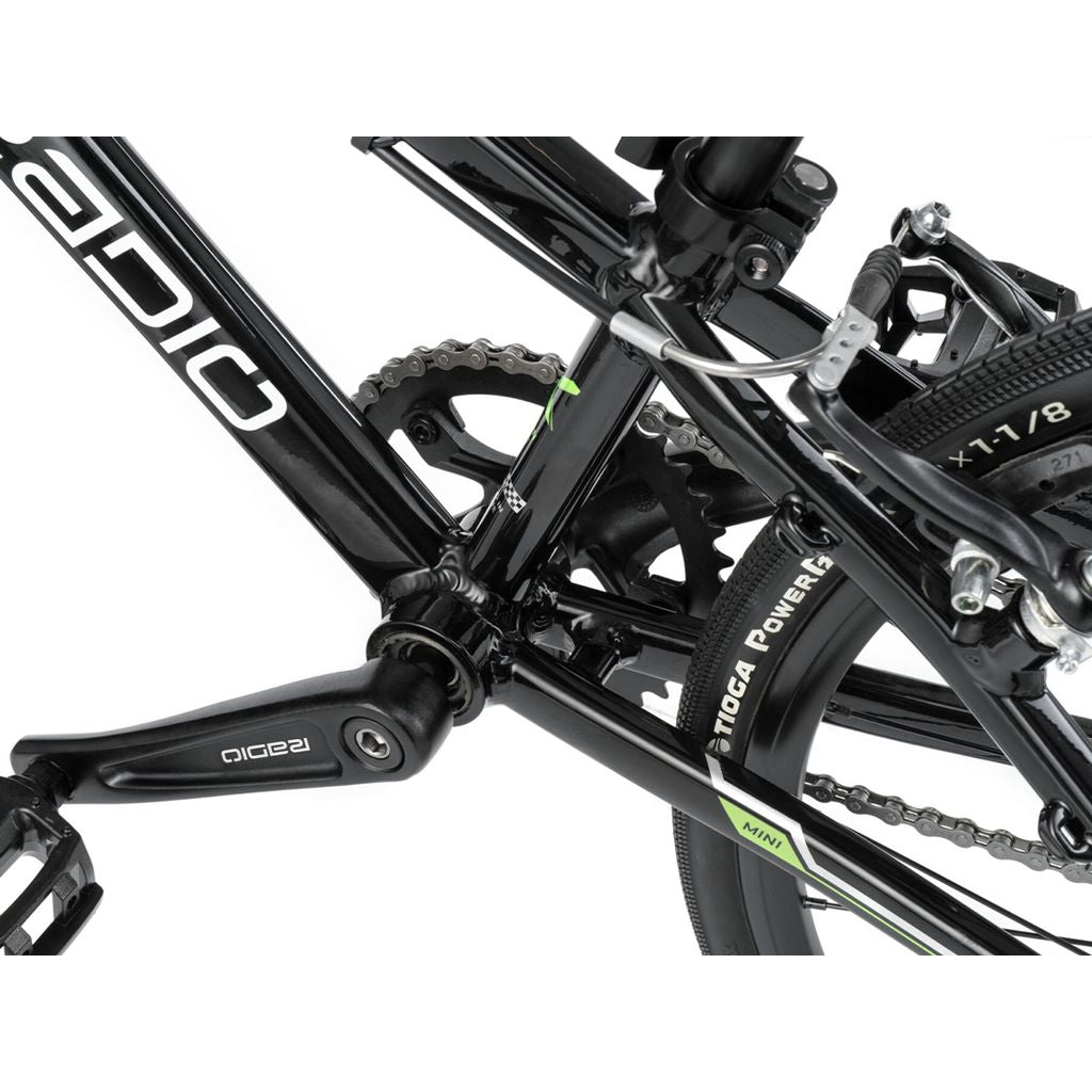 Close-up of the drivetrain and rear wheel of a black Radio Xenon Mini Bike, showing the pedal, chain, rear tire with Tioga Powerblocks, and part of the bike frame.