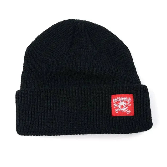 The Backbone Real Deal Beanie is a black knit cuff beanie with a folded brim, featuring the Backbone Skull logo on a red rectangular patch with white graphics and text on the front.