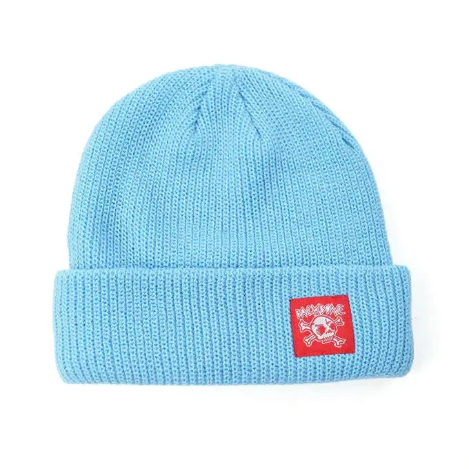 The Backbone Real Deal Beanie is a light blue cuff beanie with a folded brim and a red rectangular patch featuring the Backbone Skull logo and bold white text—perfect for adding standout style to any cold-weather outfit.