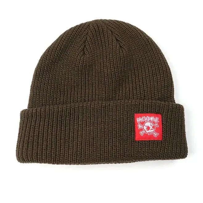 The Backbone Real Deal Beanie is a brown cuff beanie with a folded brim and a red rectangular patch featuring the Backbone Skull logo—a white skull and crossed bones.