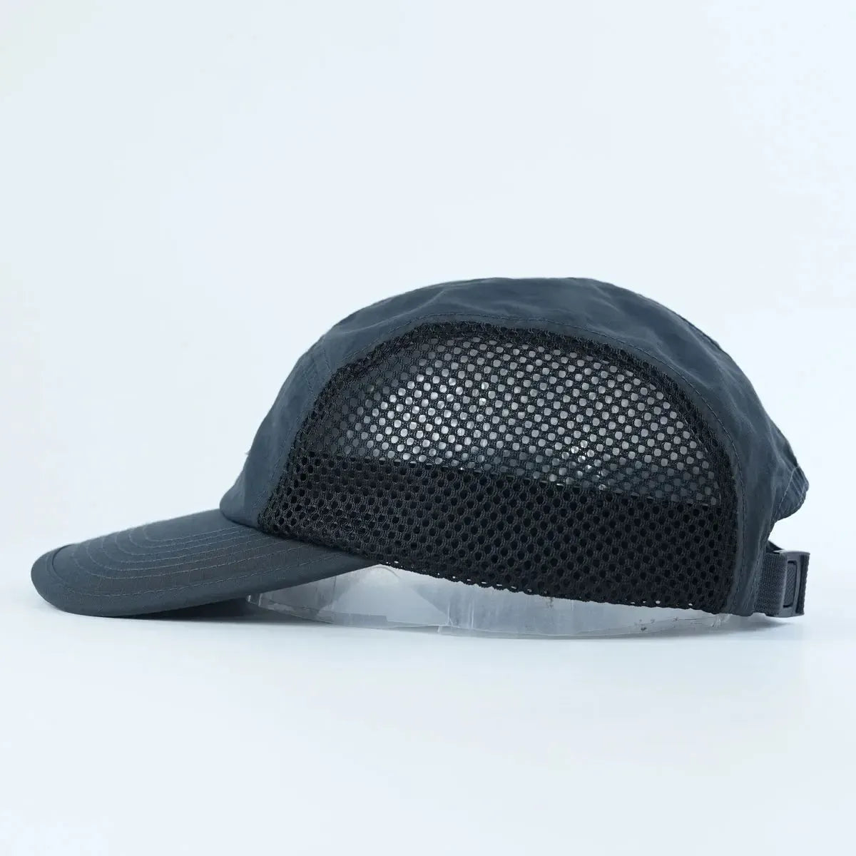 The Backbone Ride Club Hat, featuring black mesh panels, a curved brim, and an adjustable strap, is displayed in a side view against a plain white background—this versatile runners-style cap is crafted for optimal comfort and breathability on the go.